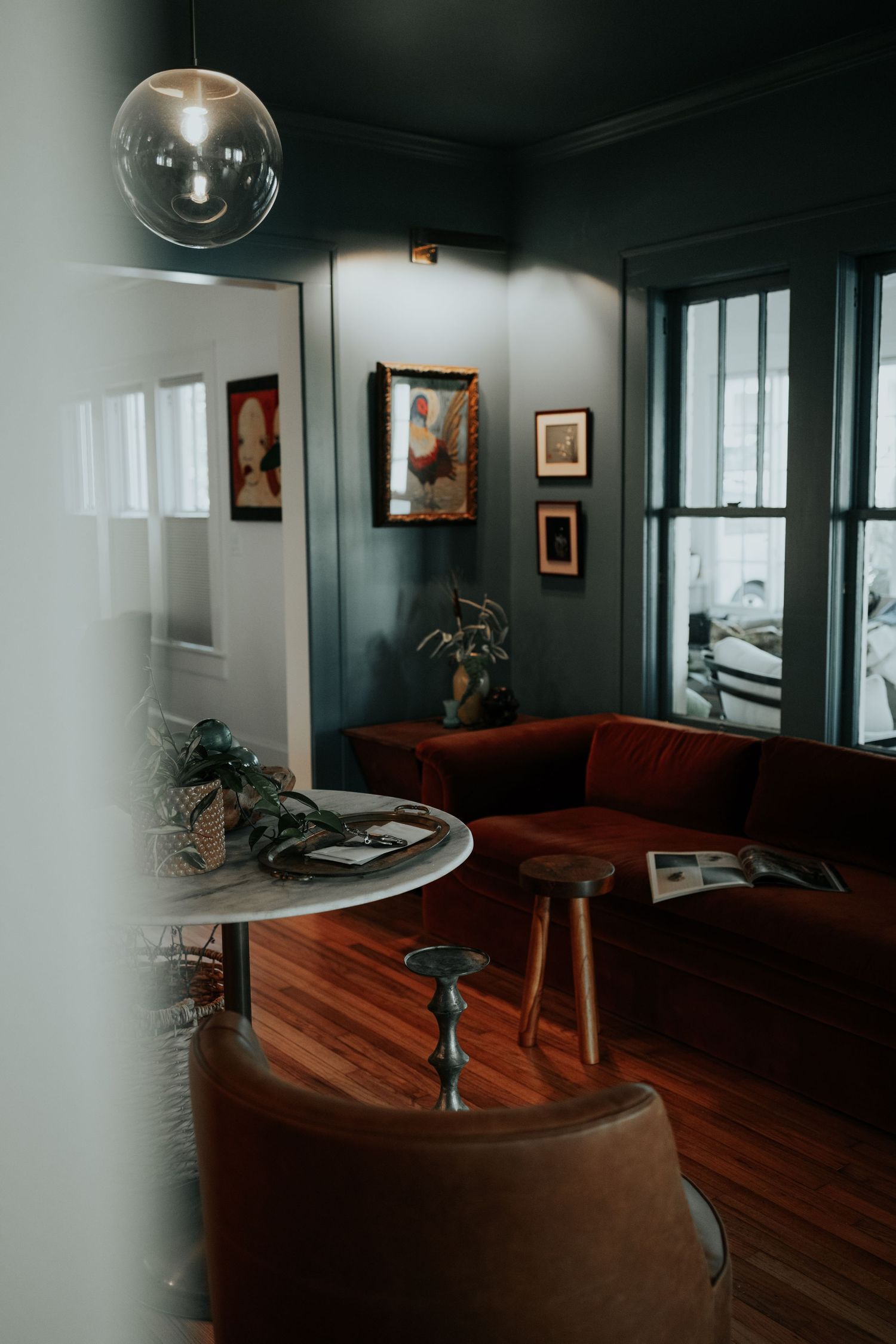 Modern interior room with dark walls, wooden floors and artistic lighting fixtures.