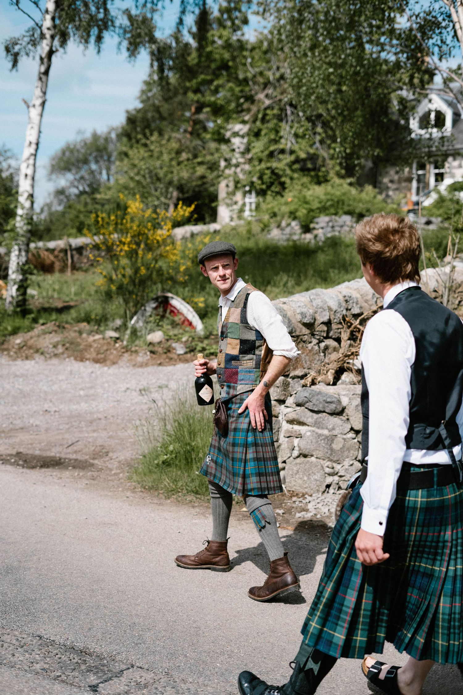 Wedding party in traditional Scottish kilts walking along a rural path.