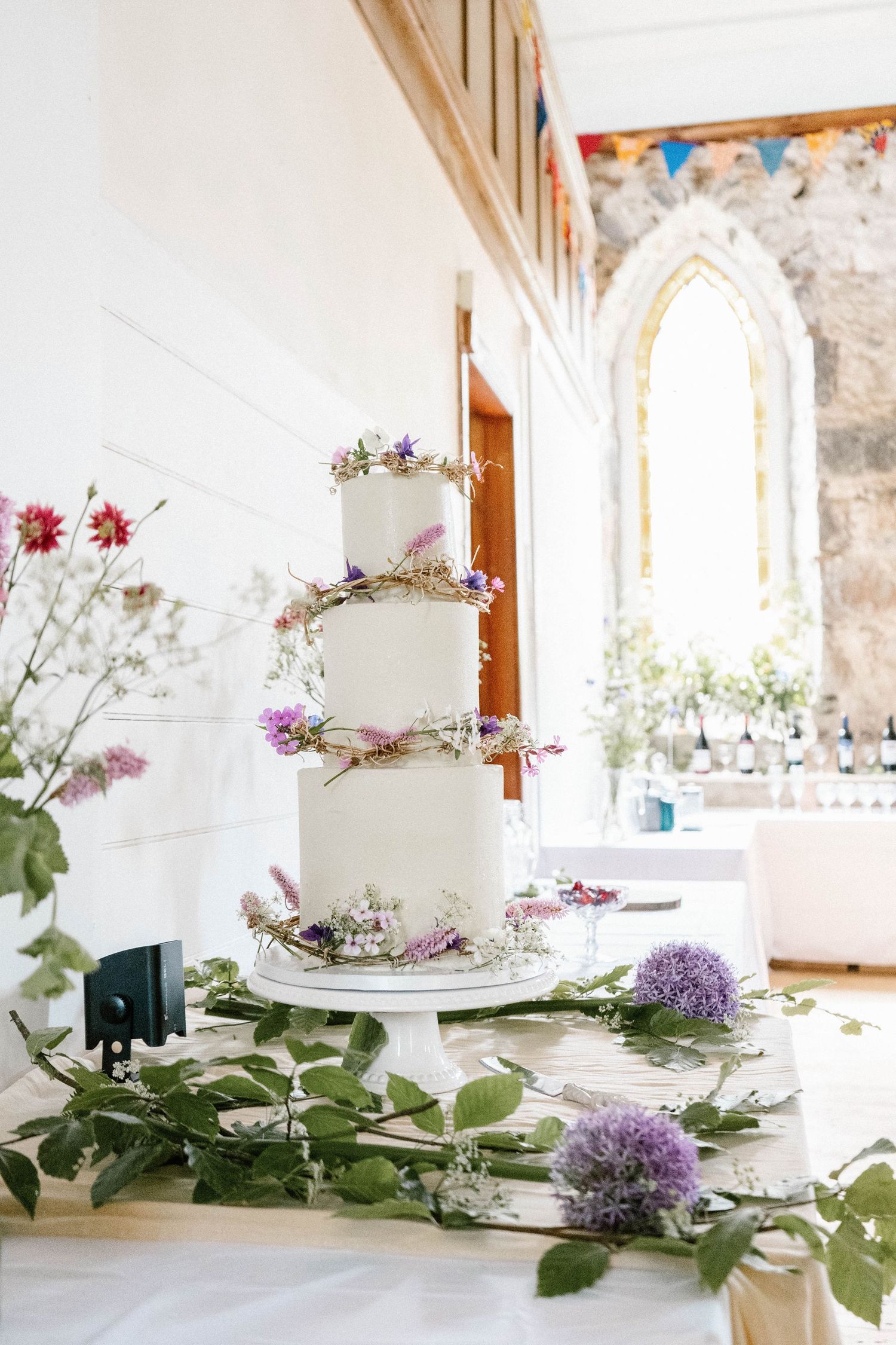 Elegant white wedding cakes decorated with delicate flowers on a table with natural light.
