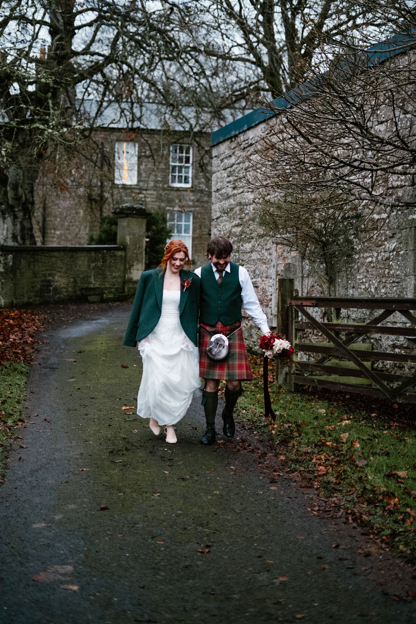 Wedding couple walking along a stone path surrounded by historic architecture.