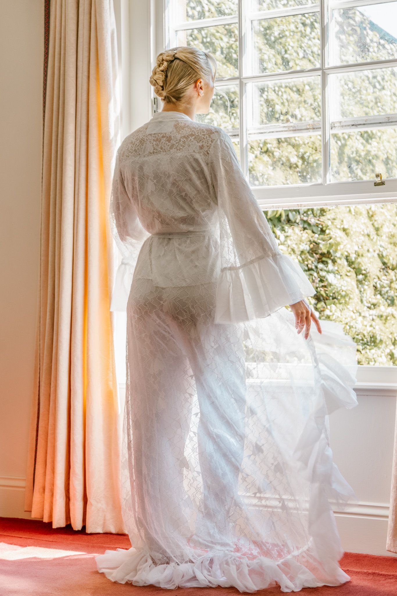 Flowing white wedding dress swirling in natural light by large windows.