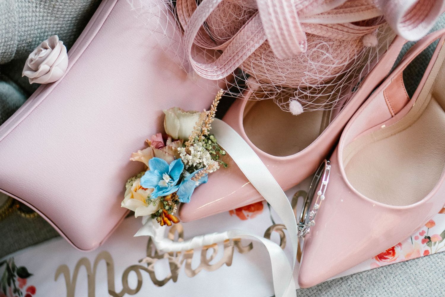 Elegant pink bridal shoes with delicate floral details arranged with wedding accessories.