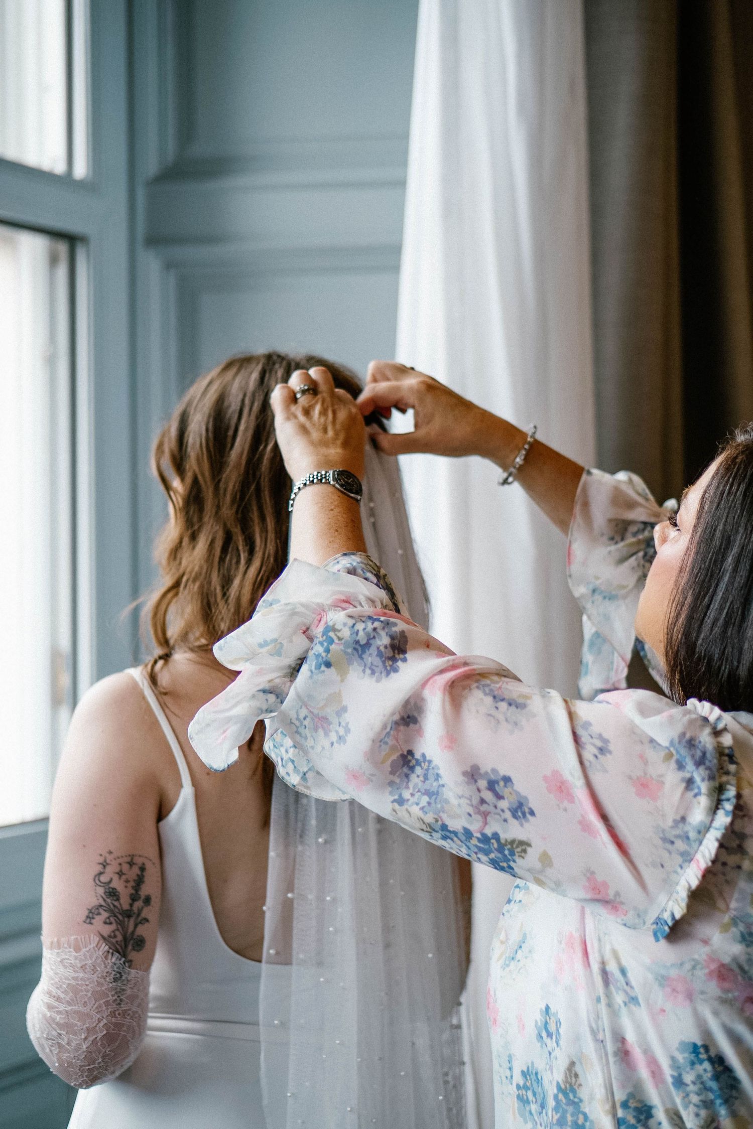 Wedding preparation scene with flowing white curtains and floral dress details.
