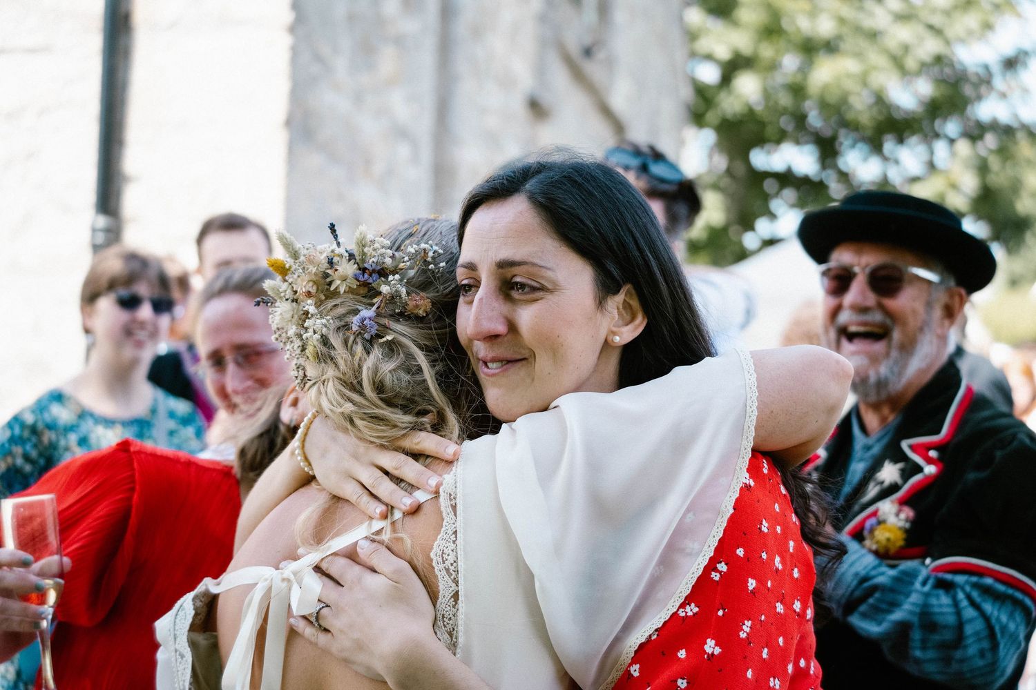 Wedding guests celebrate outdoors with joyful embraces and festive expressions.