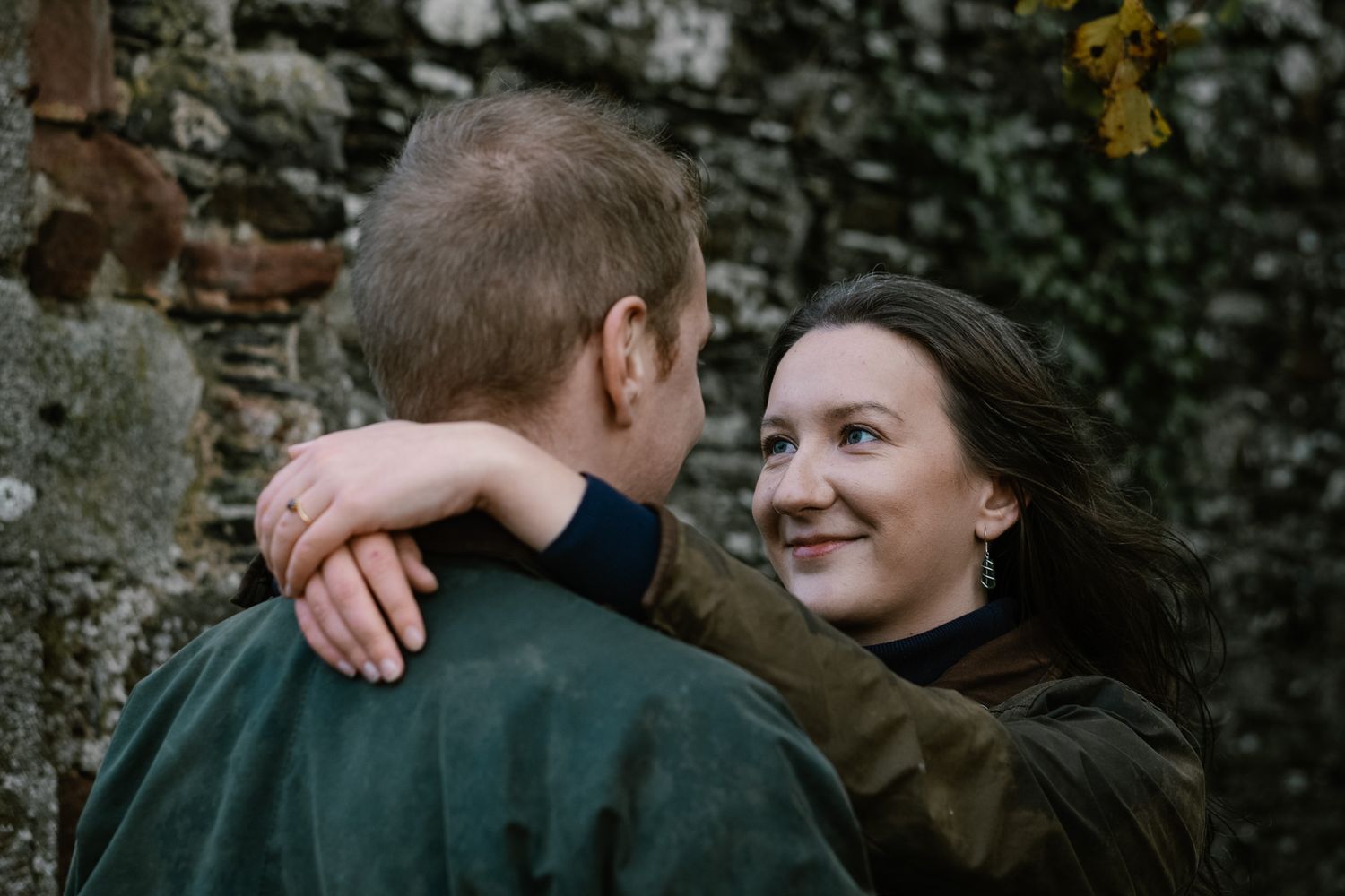 Intimate moment captured against a dark ivy-covered wall outdoors.