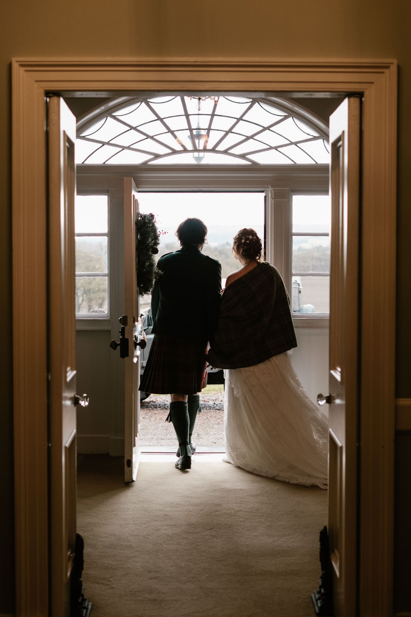Silhouettes walk through a series of doorways in an elegant indoor corridor.