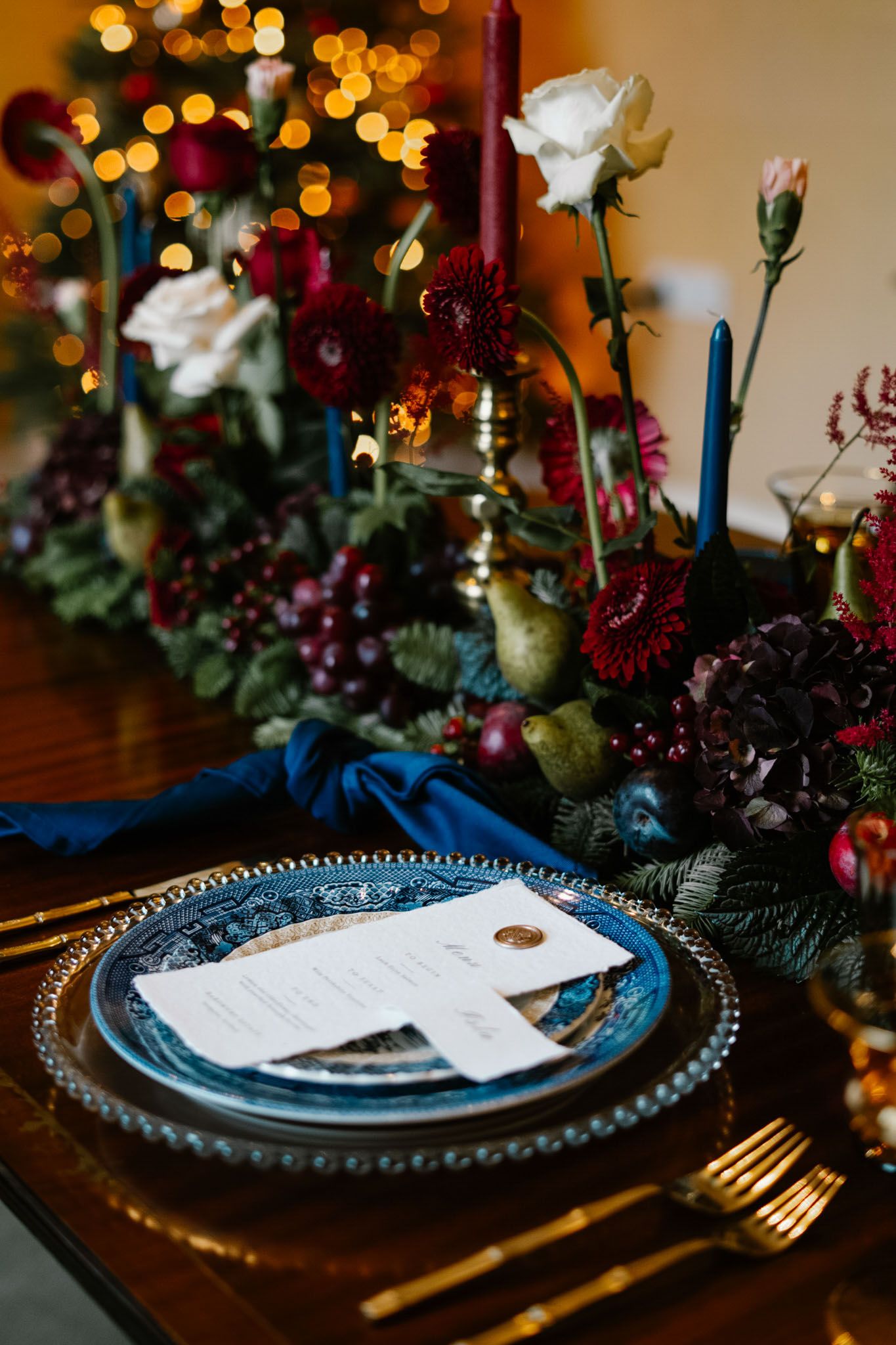 Elegant place setting with blue plates, gold flatware and floral centerpiece.
