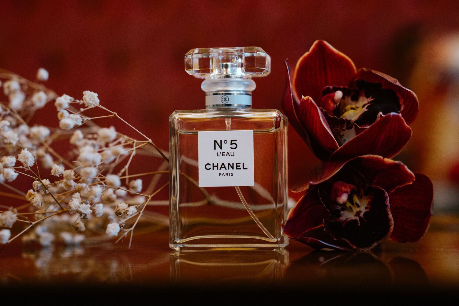 Elegant Chanel No 5 perfume bottles arranged with floral elements on dark background.