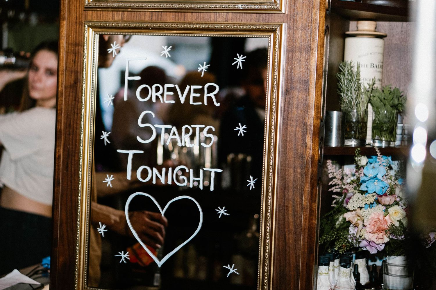 Chalkboard signs with romantic messages and hearts drawn in white chalk displayed in wooden frames.