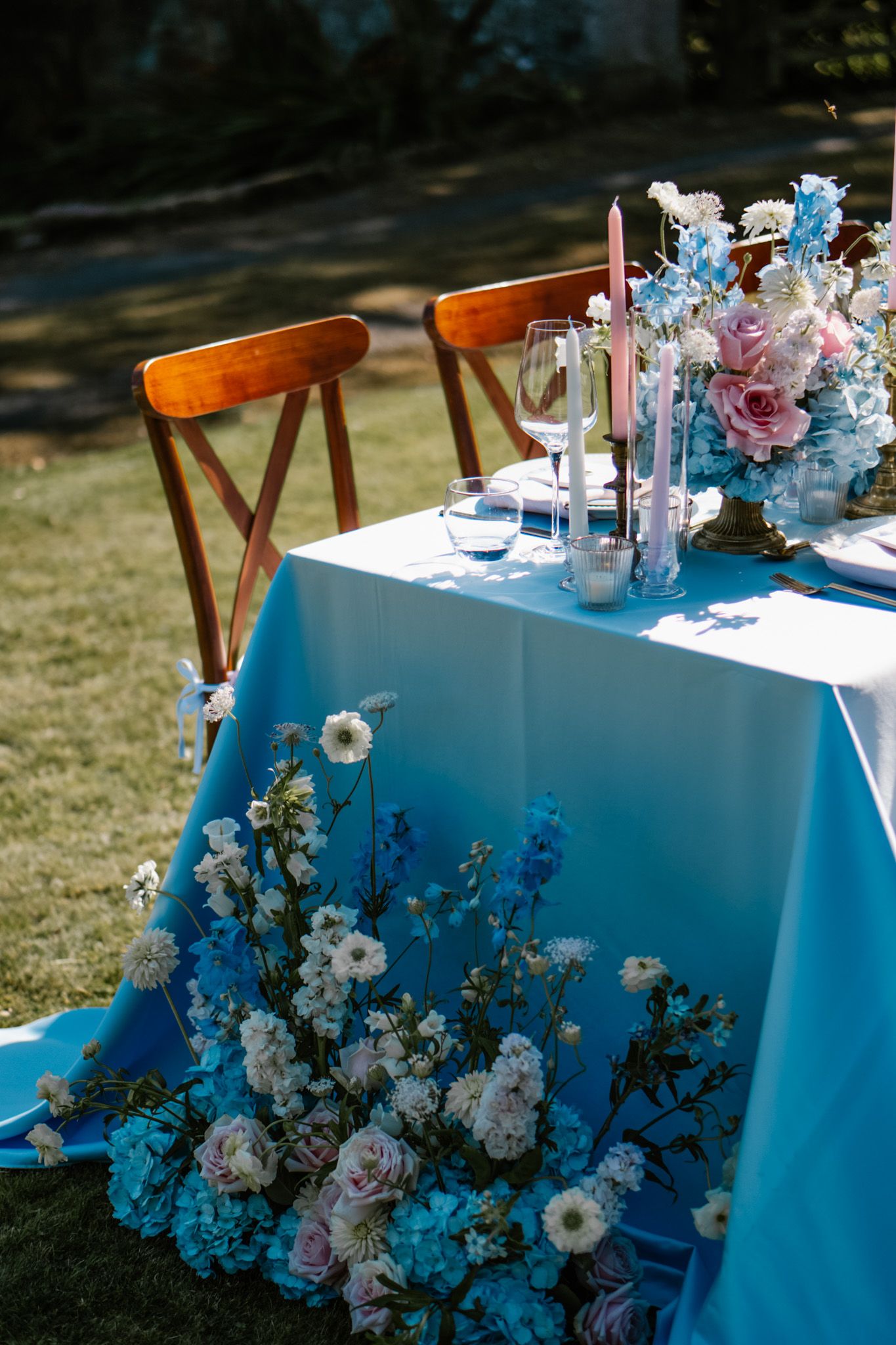 Wedding reception table with blue tablecloth decorated with delicate floral arrangements.