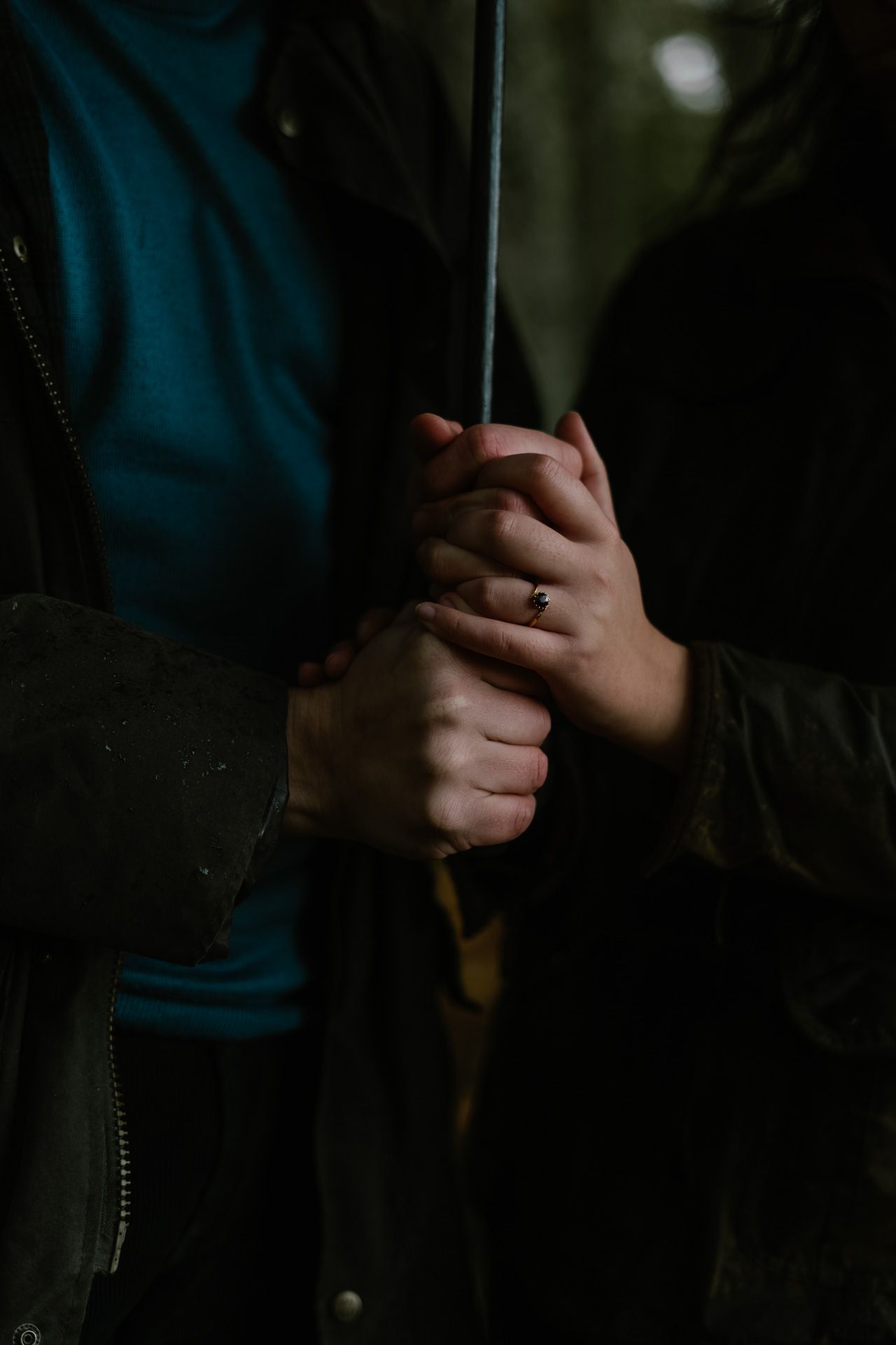 Close-up shot of intertwined hands in dim lighting creating an intimate atmosphere.
