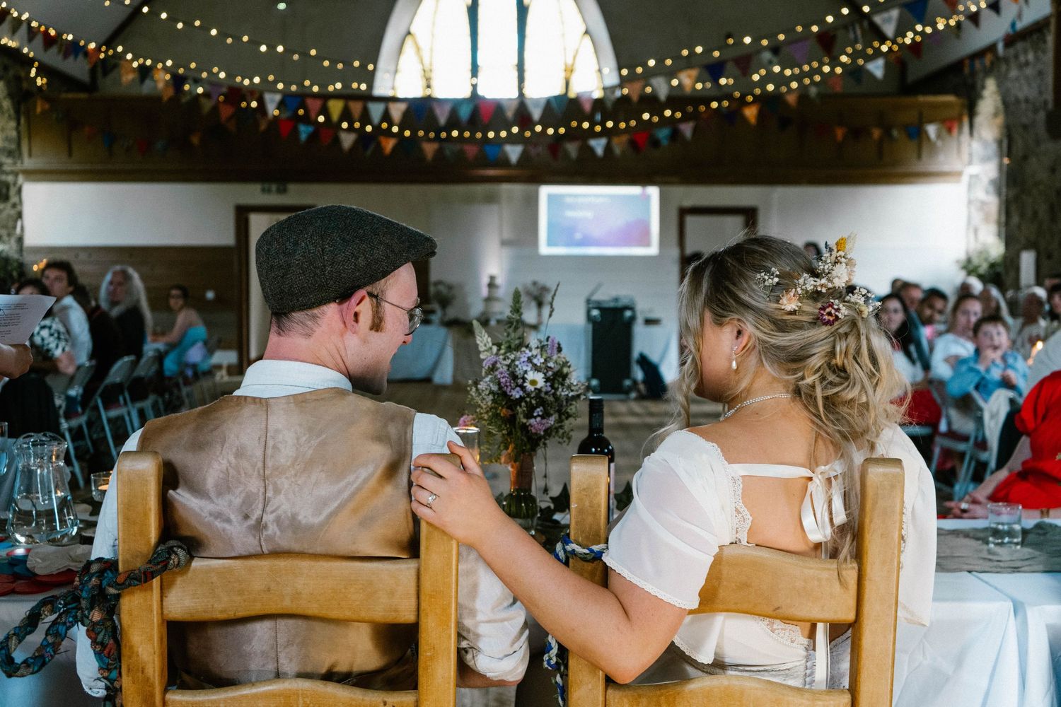 Wedding reception venue decorated with romantic string lights and wooden beams.