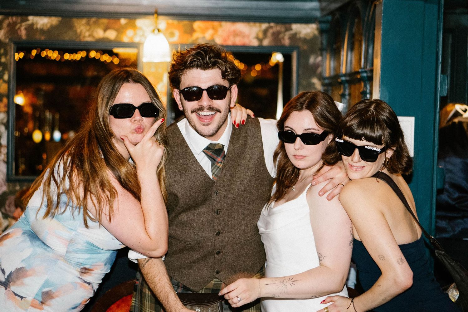 Wedding party wearing sunglasses and dancing at an indoor reception.