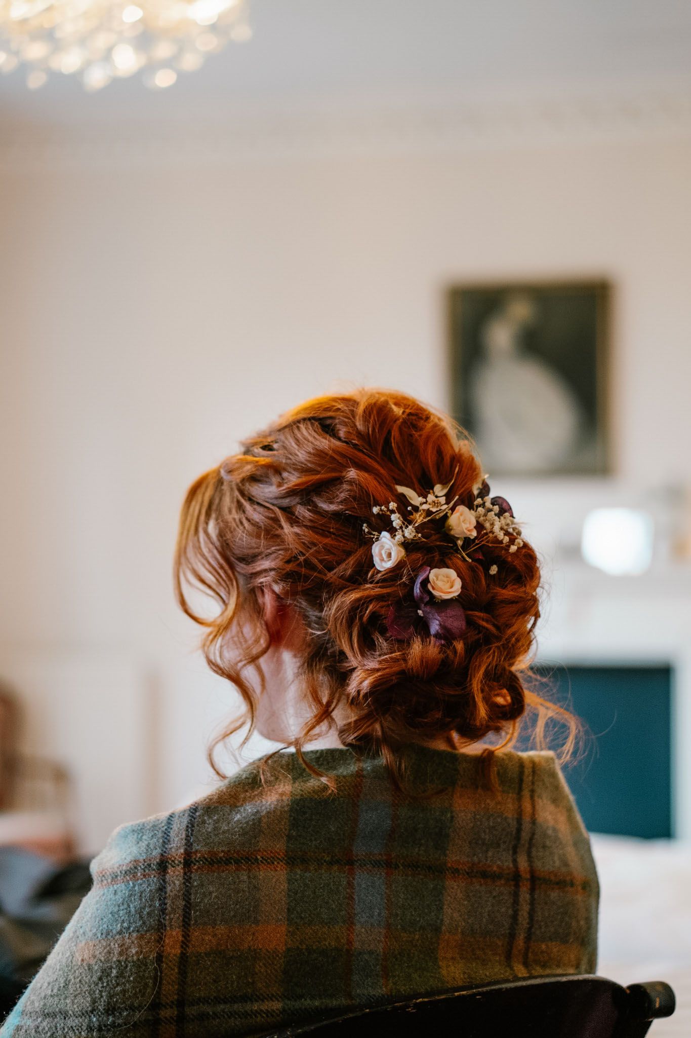 Close-up view of an elegant bridal hairstyle with delicate floral accessories and auburn curls.