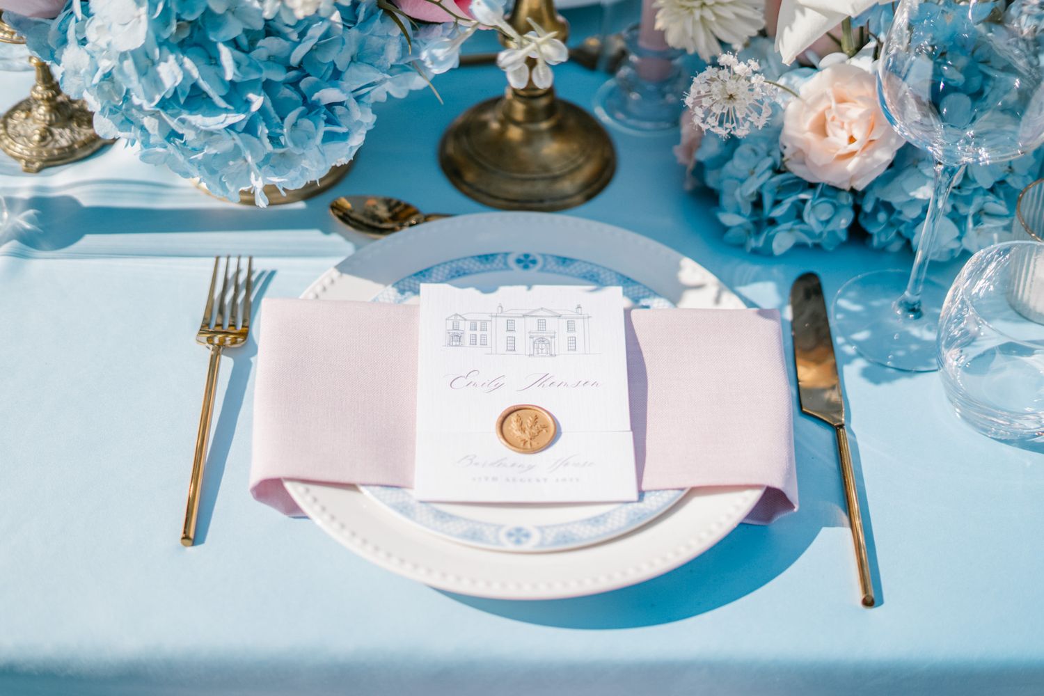 Elegant wedding table settings with blue hydrangeas and gold accents create a romantic atmosphere.
