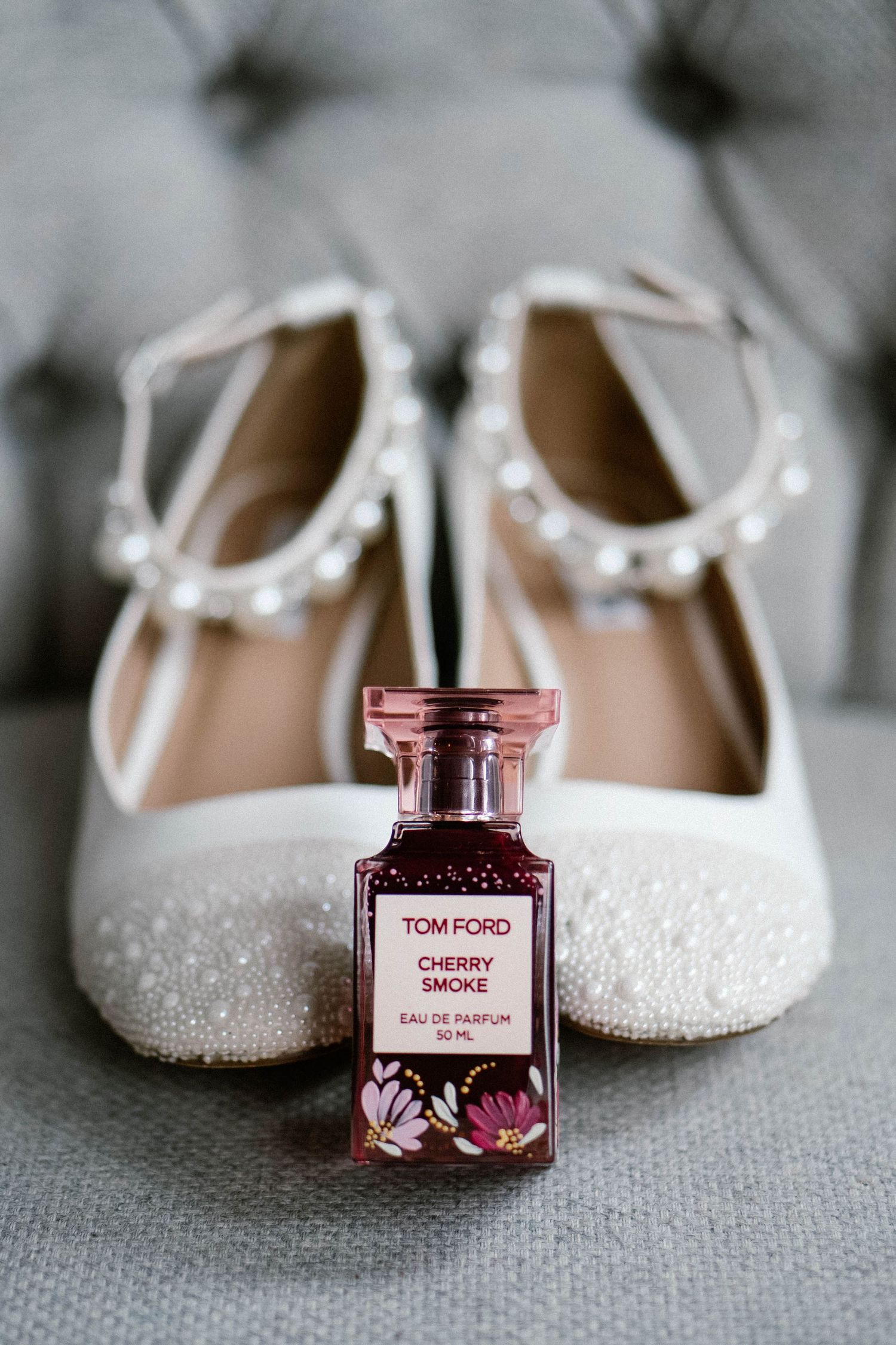 Elegant white bridal shoes with sparkles displayed alongside a Tom Ford rose perfume bottle.