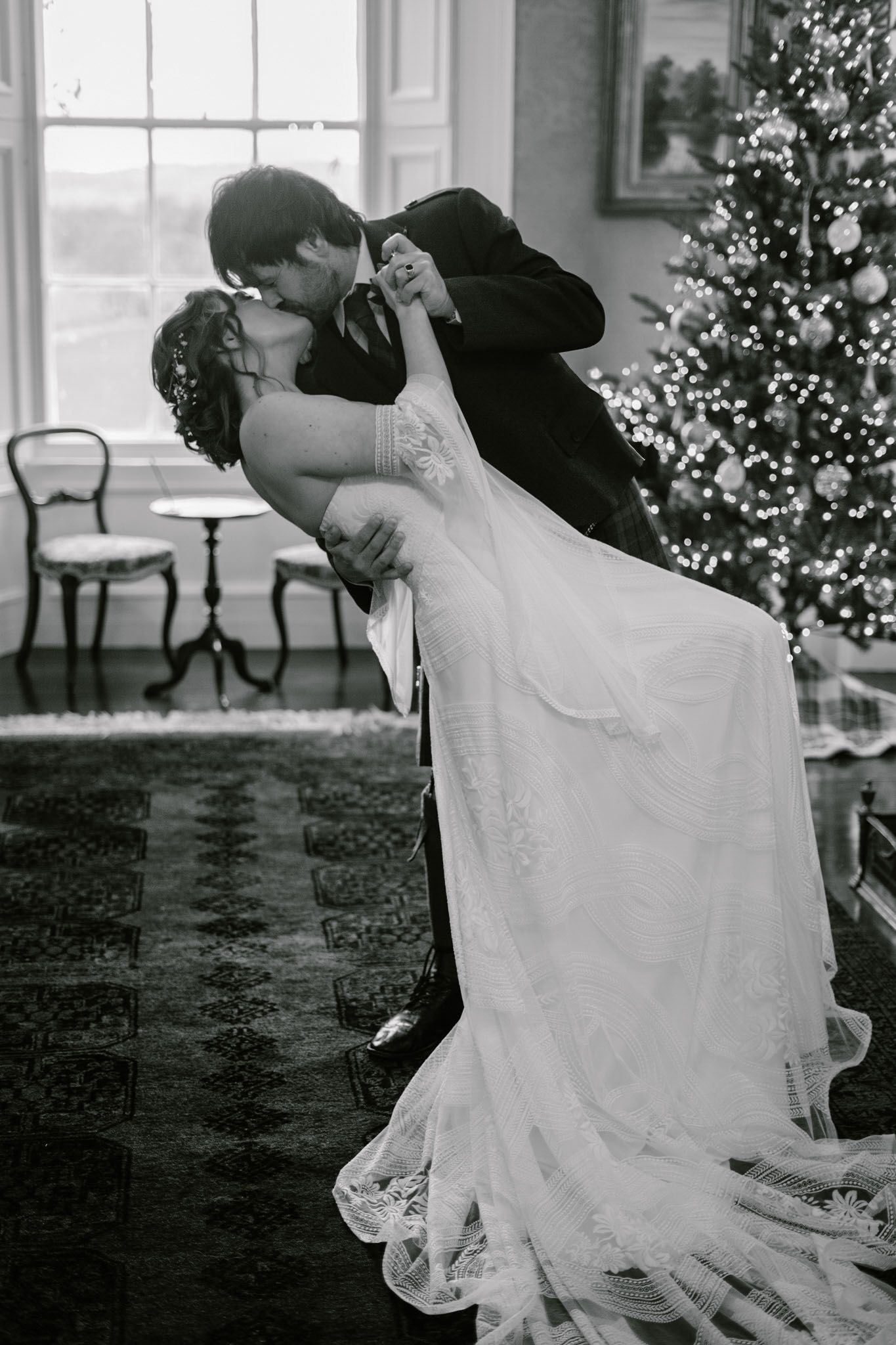 Black and white romantic dance sequence at wedding reception with decorated Christmas trees.