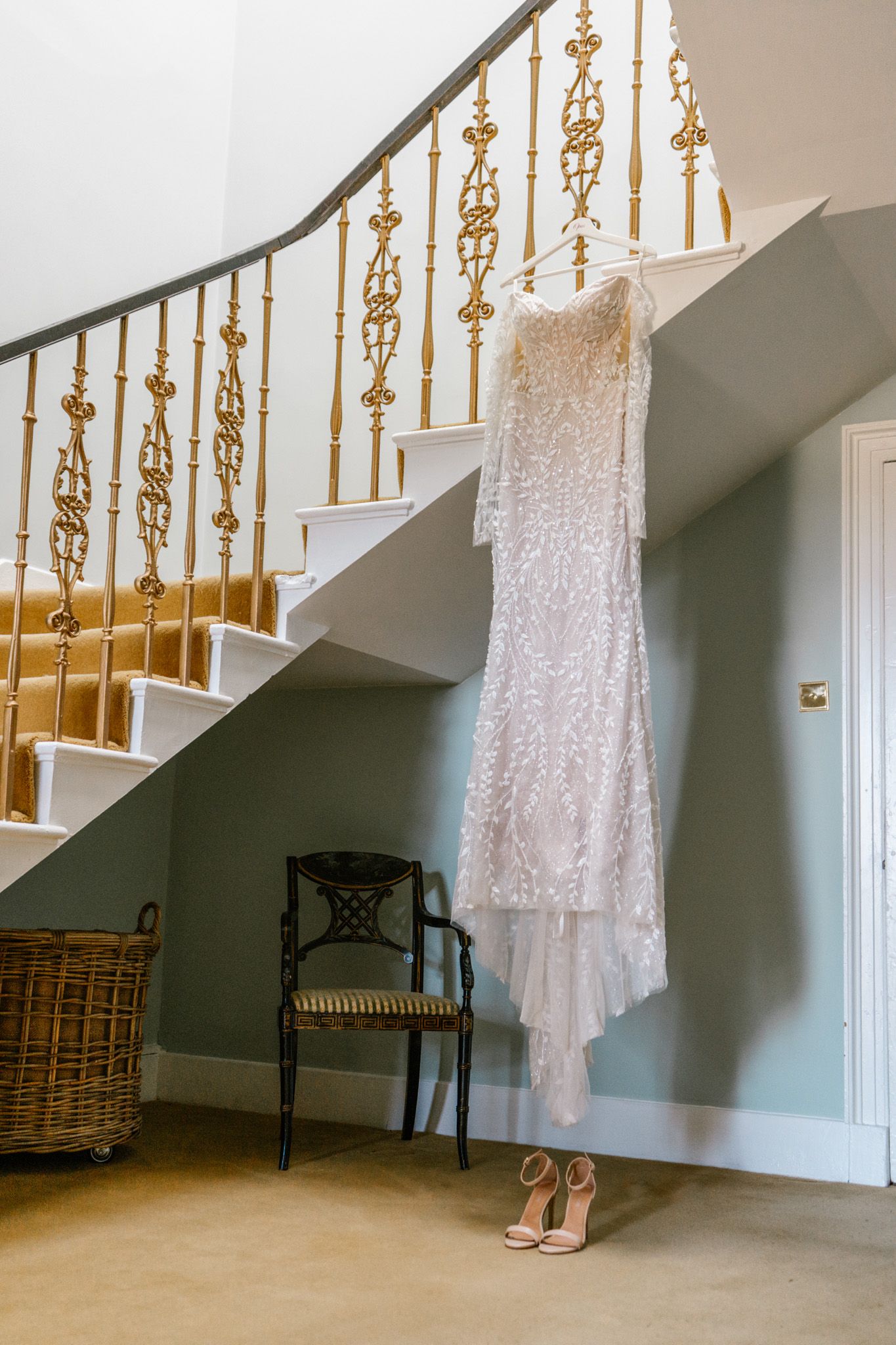 Wedding dress and heels displayed along elegant staircase with gold railings.