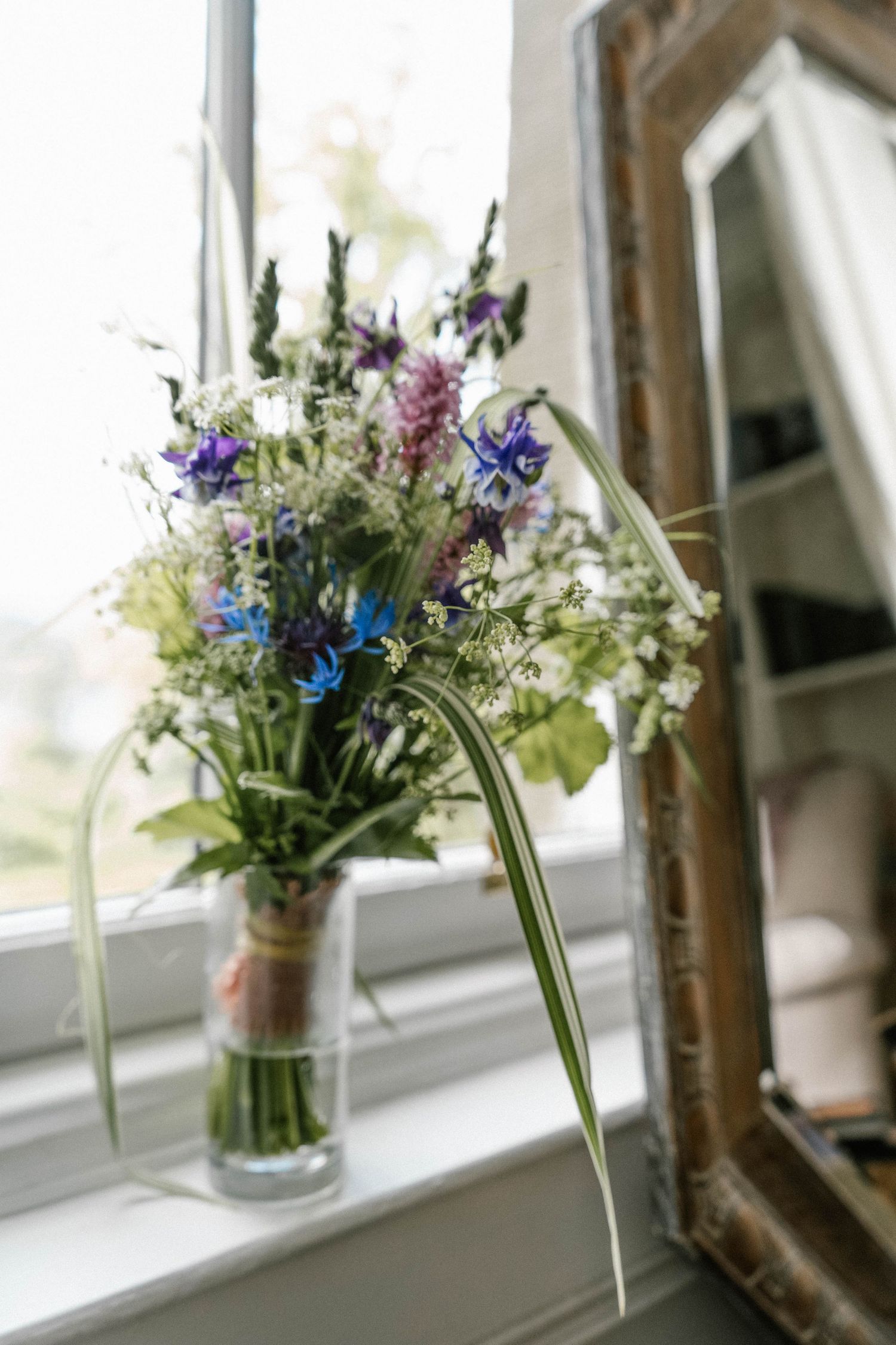 Wildflower bouquets in glass jars displayed along a bright windowsill.