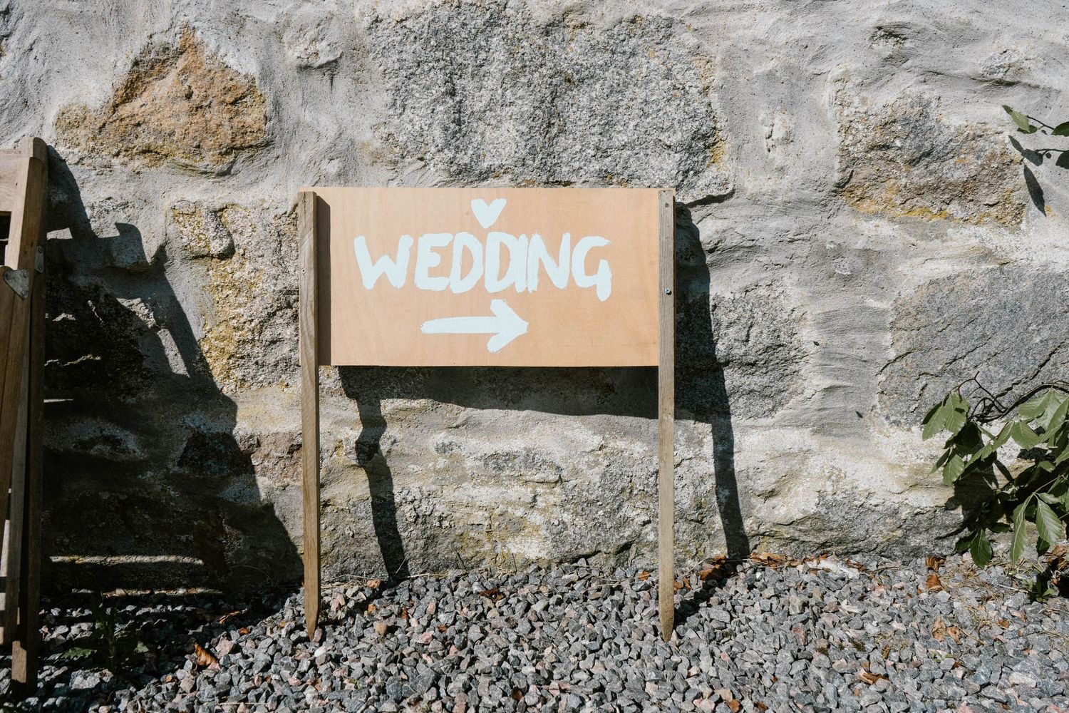 Rustic stone wall with directional wedding signage pointing the way.