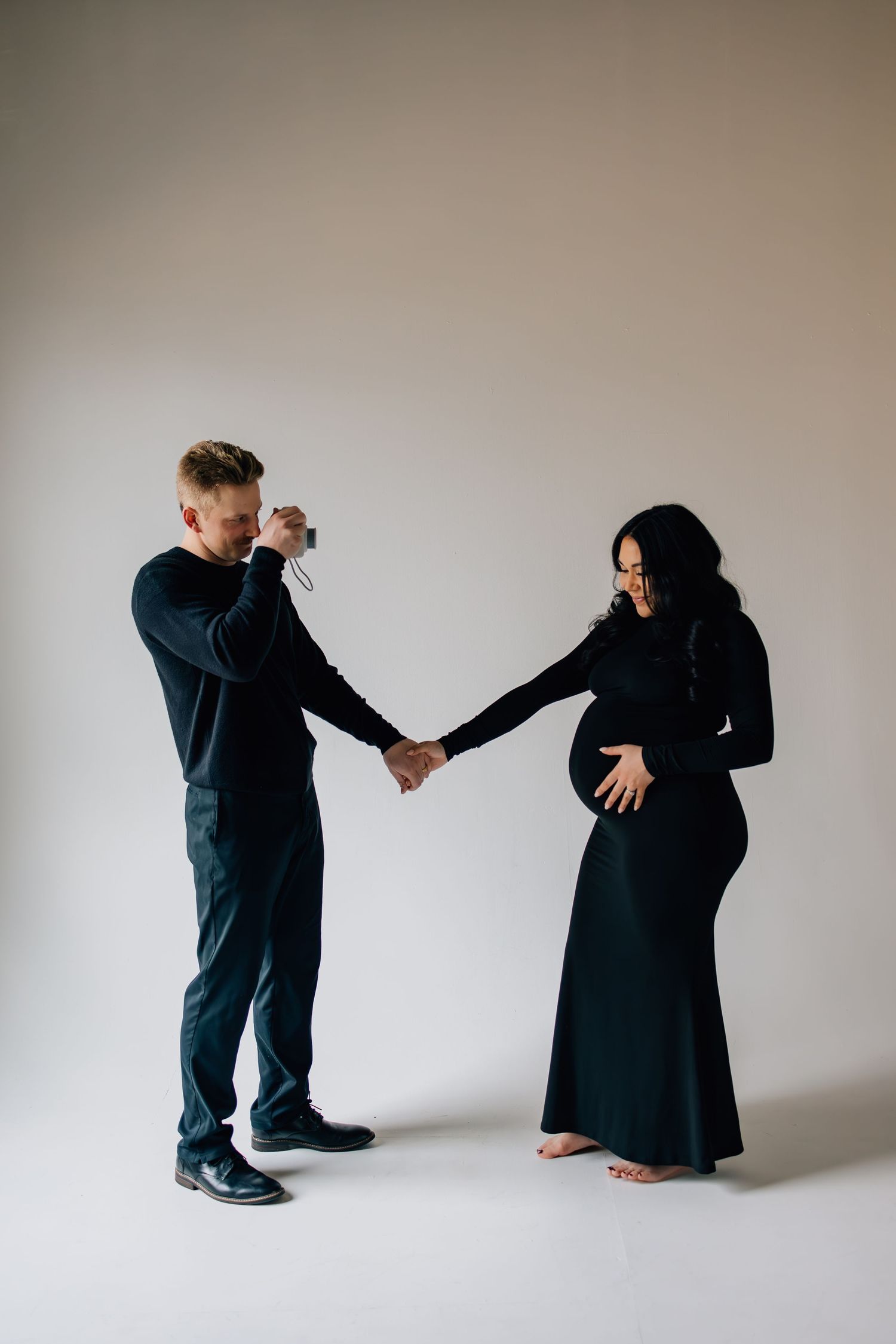 Maternity photography featuring the father-to-be taking a polaroid photograph of the expectant mother