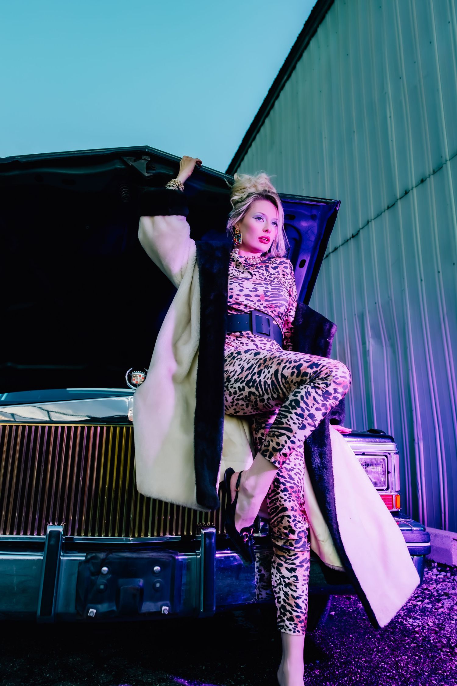 Editorial-style image featuring woman in 80s attire sitting in front of a vintage limo