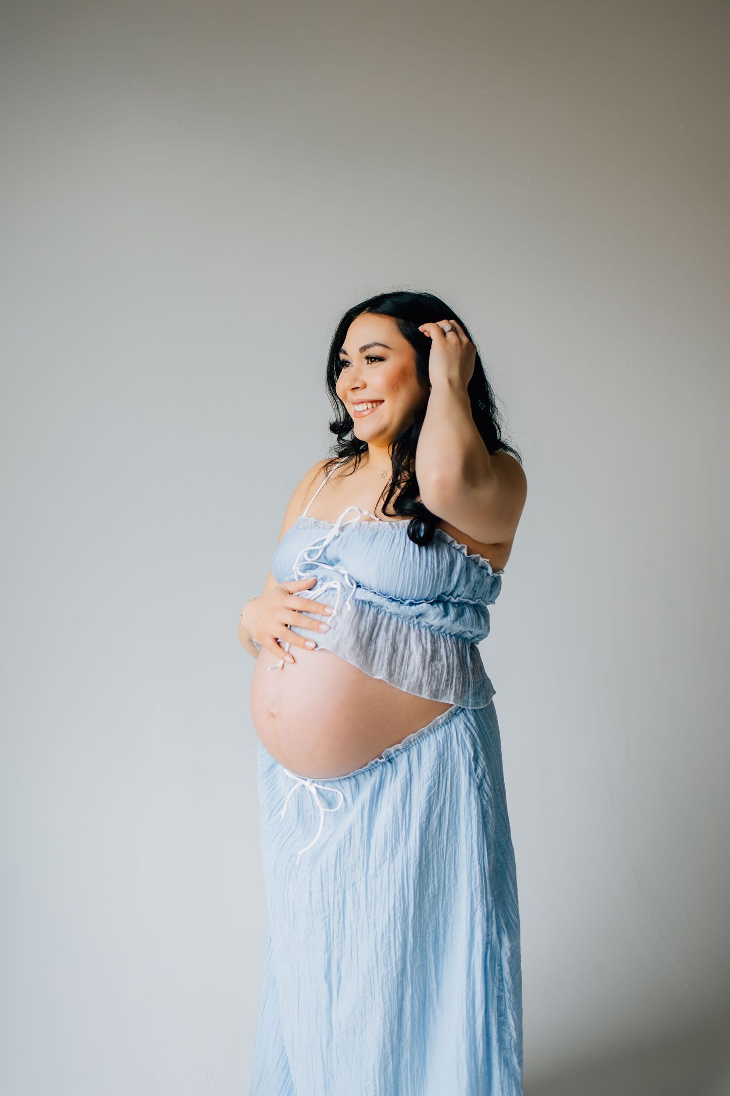 Maternity photography featuring an expectant mother in a stunning baby blue set in a cozy, Utah photo studio
