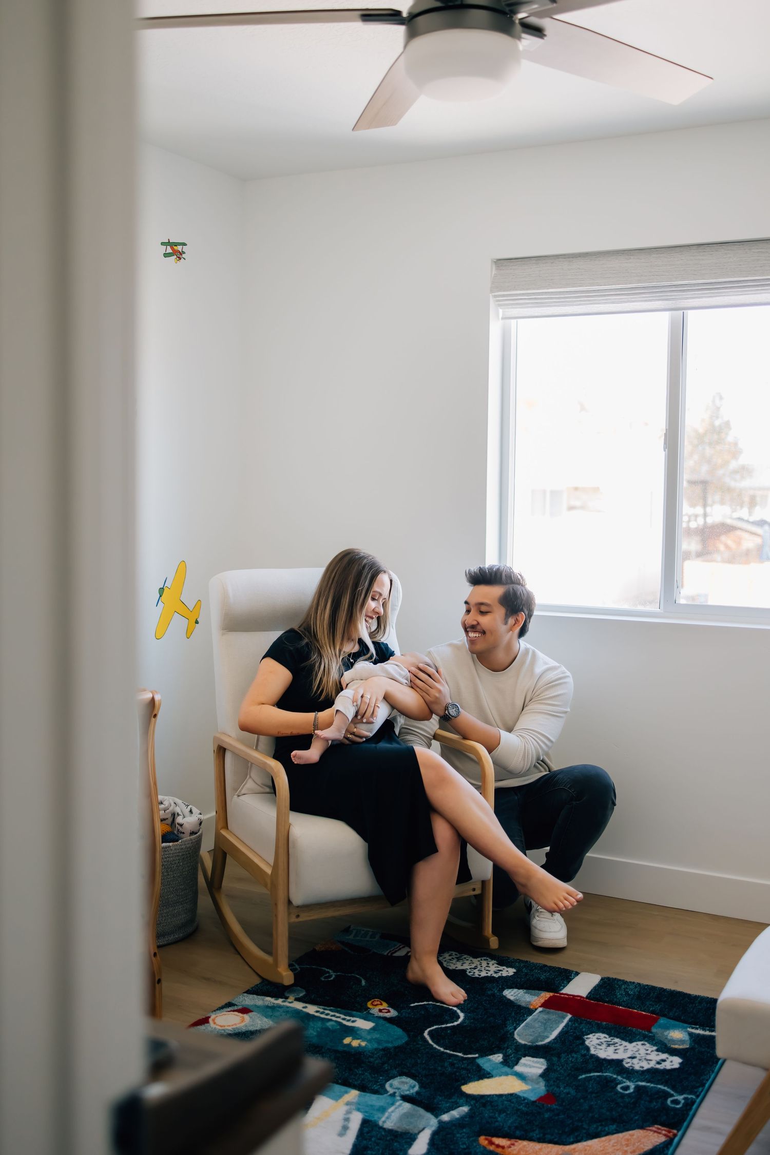 In-home lifestyle newborn photography in Salt Lake City featuring a mother holding her baby in her home surrounded by her husband as well