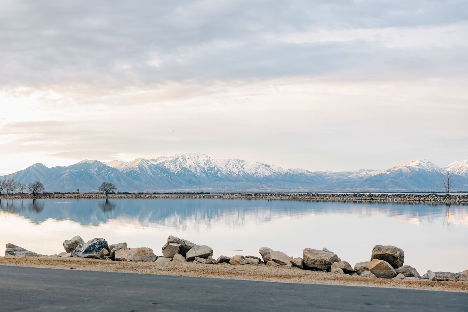 Landscape photography of a stunning location along Utah Lake featuring mountain range, water, and rocks