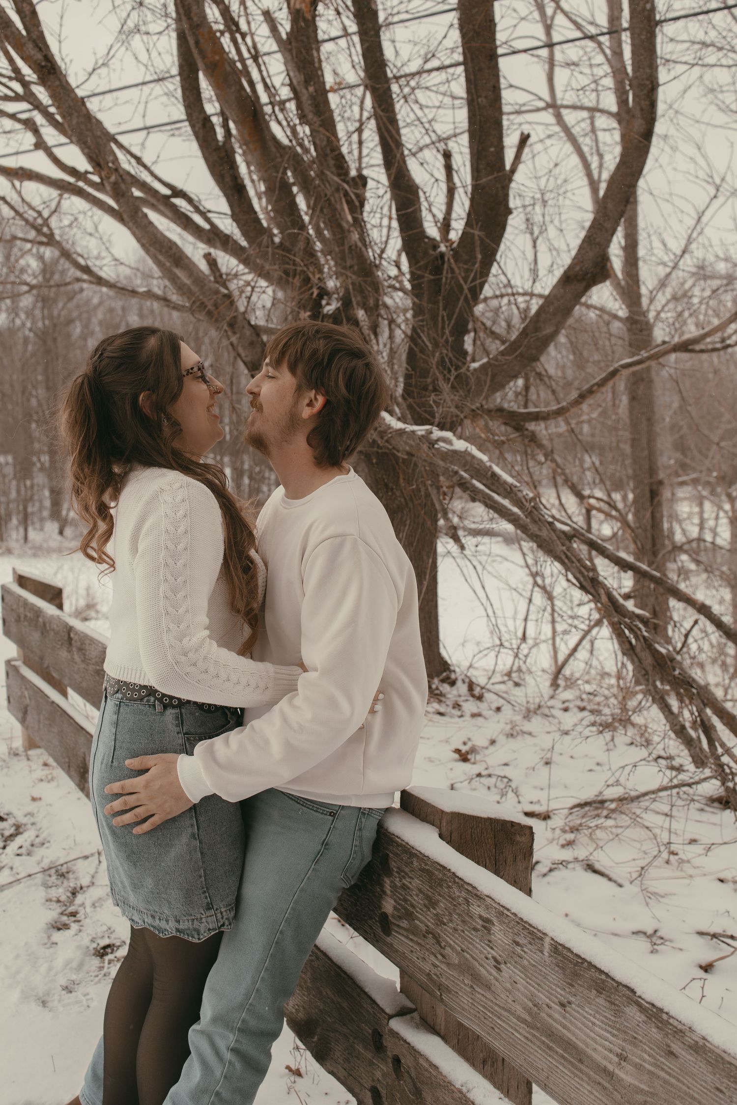 Engaged couple kissing at covered bridge in Ashtabula Ohio by Gypsy Lens Photography. Moody, vintage, documentary wedding photographer.