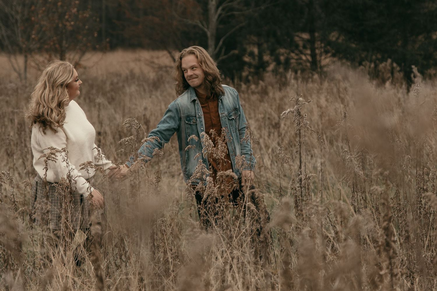 Couple walking through tall grass in Lake County Ohio by Gypsy Lens Photography. Moody, vintage, documentary wedding photography.