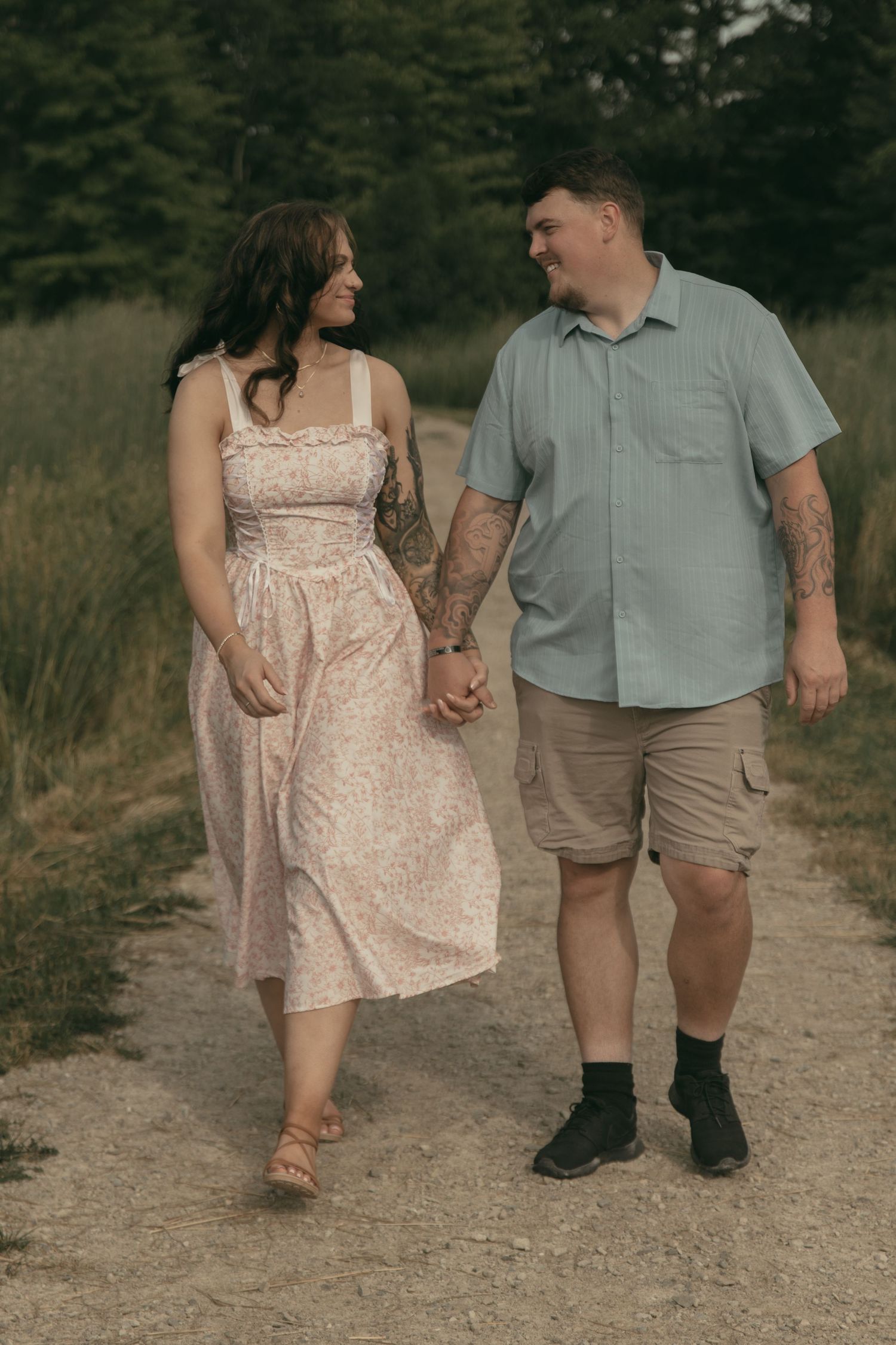 Engaged couple smiling in a meadow in Lake County Ohio by Gypsy Lens Photography. Moody, filmy, vintage, documentary wedding photography