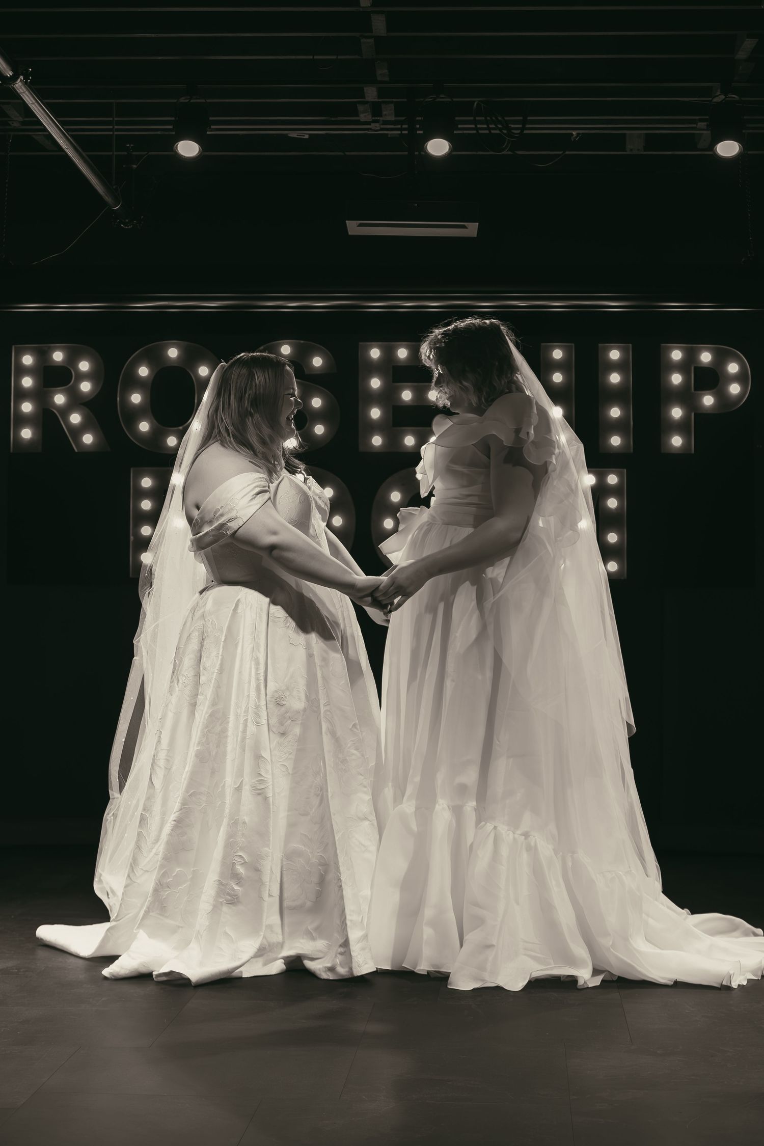 Two brides dancing on stage at wedding in Cleveland Ohio by Gypsy Lens Photography. Moody, filmy, vintage, documentary wedding photography.