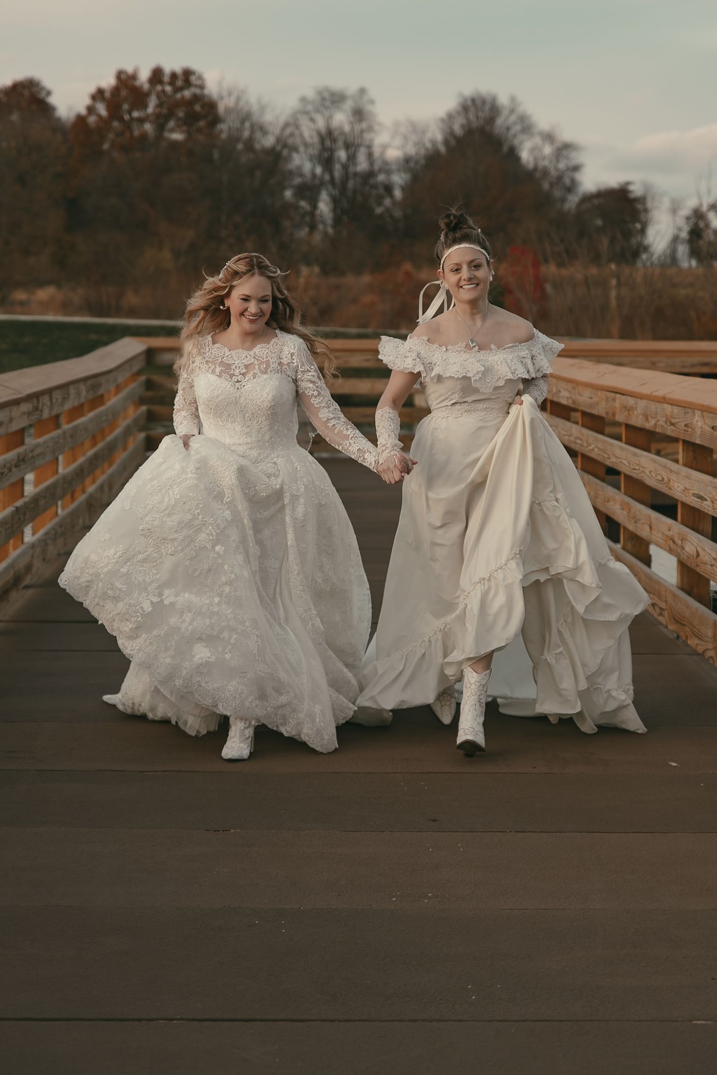 Two brides in flowing white gowns run joyfully together  in Lake County Ohio by Gypsy Lens Photography. Moody, vintage, documentary wedding