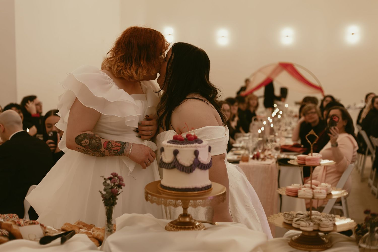 Brides kiss before cutting cake in Cleveland Ohio by Gypsy Lens Photography. Moody, filmy, vintage, documentary wedding photography.