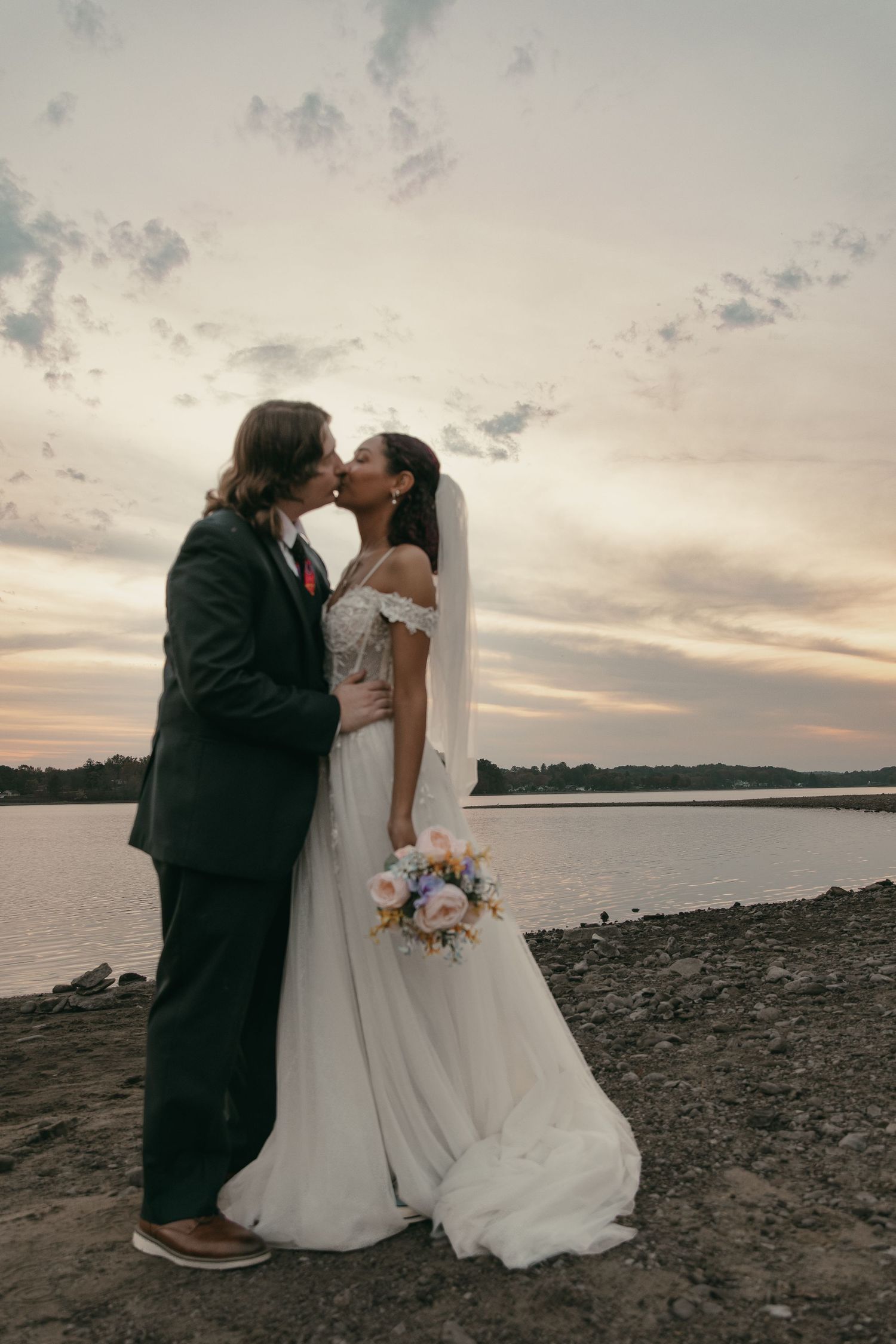 Bride and groom kissing at sunset at a beach in Cleveland Ohio by Gypsy Lens Photography. Moody, vintage, documentary wedding photography.