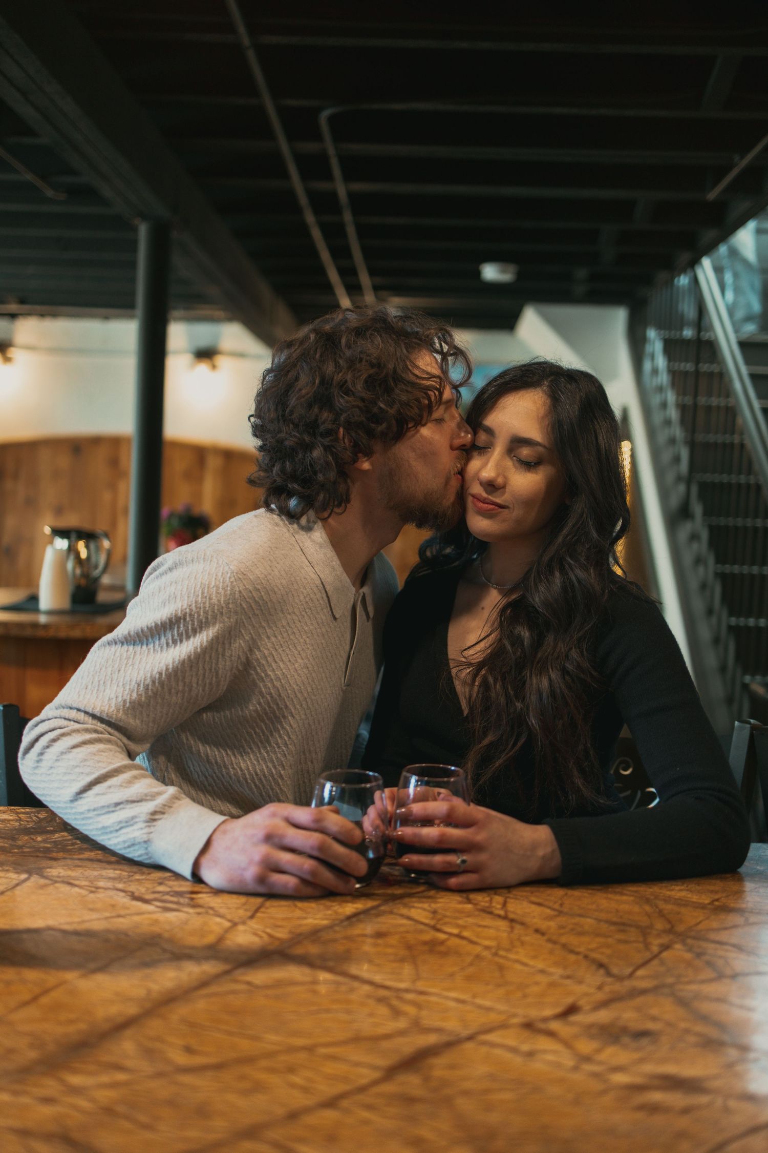 Engaged couple kissing at wine cellar in Cleveland Ohio by Gypsy Lens Photography. Moody, vintage, documentary wedding photographer.