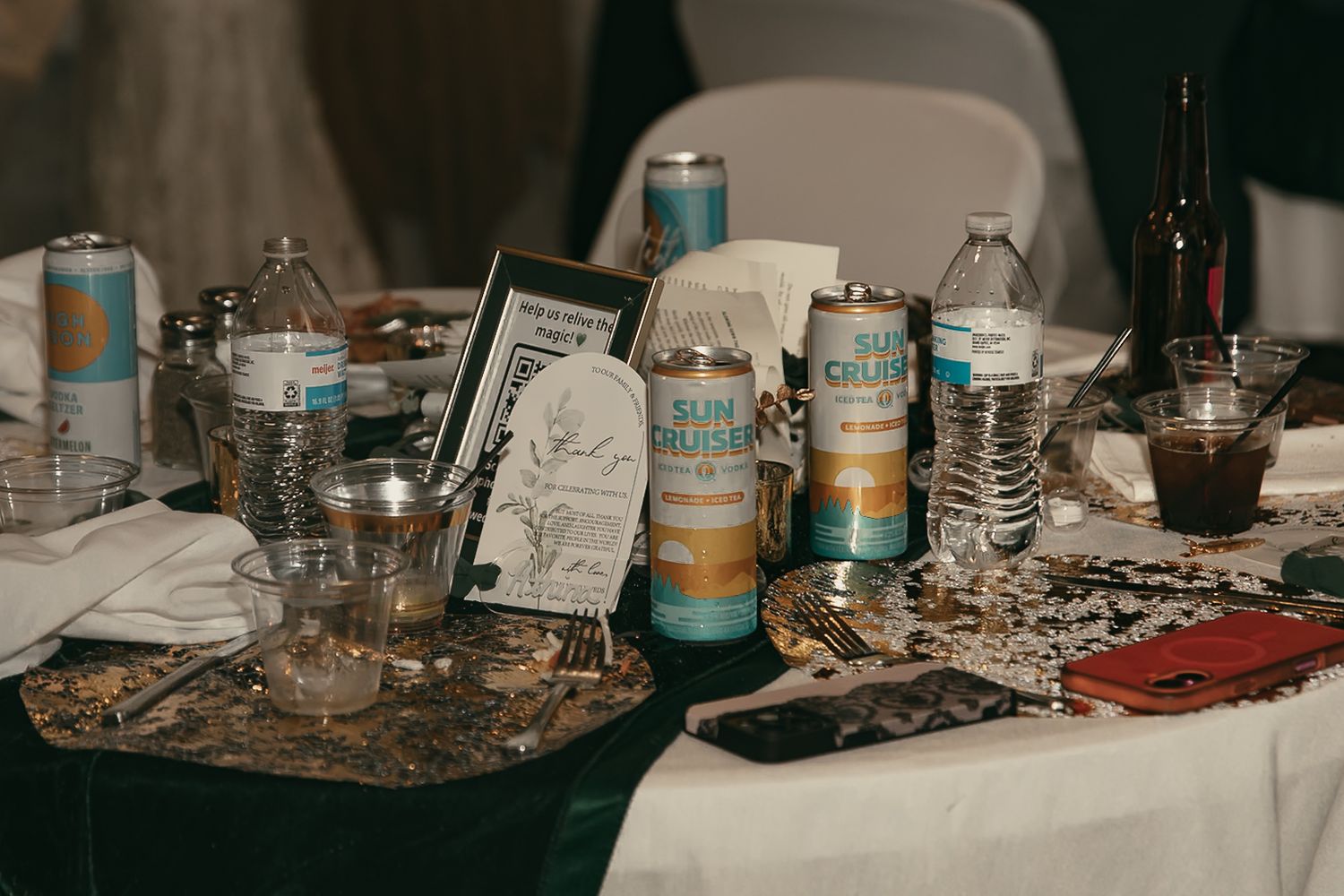 Wedding reception table with scattered drinks, cans, and decorative items in moody lighting by Gypsy Lens Photography in Lake County Ohio.