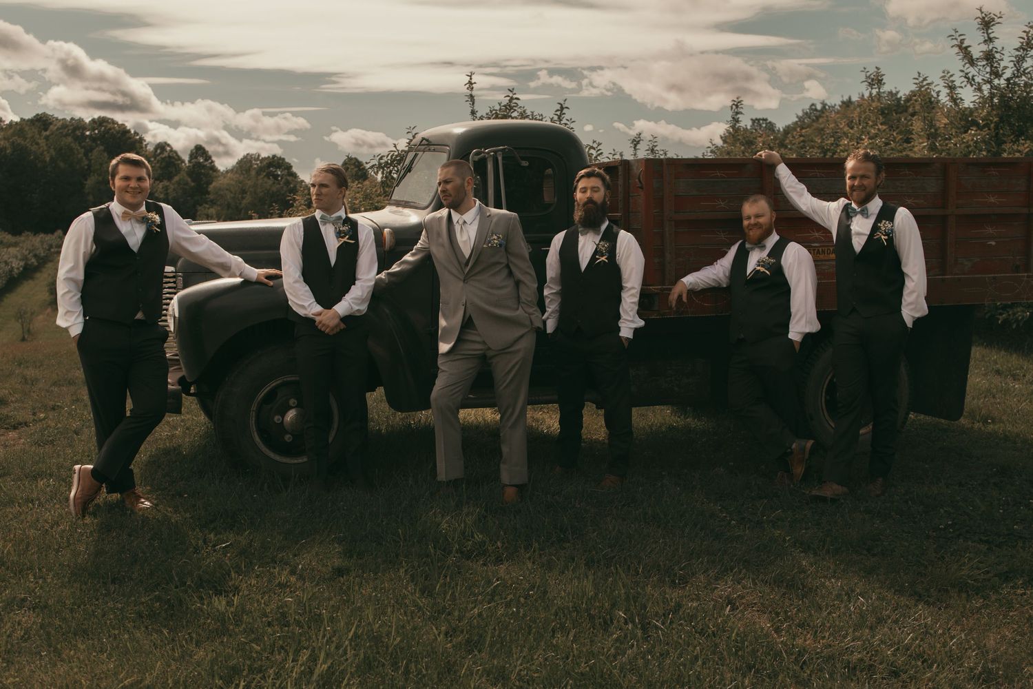 Groomsmen relaxed in field on wedding day in Ashtabula Ohio by Gypsy Lens Photography. Moody, vintage, nostalgic documentary wedding.