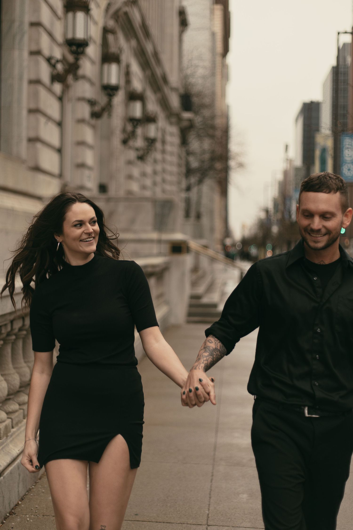 Couple playfully running in big city of Cleveland Ohio by Gypsy Lens Photography. Moody, nostalgic, vintage, documentary wedding photography