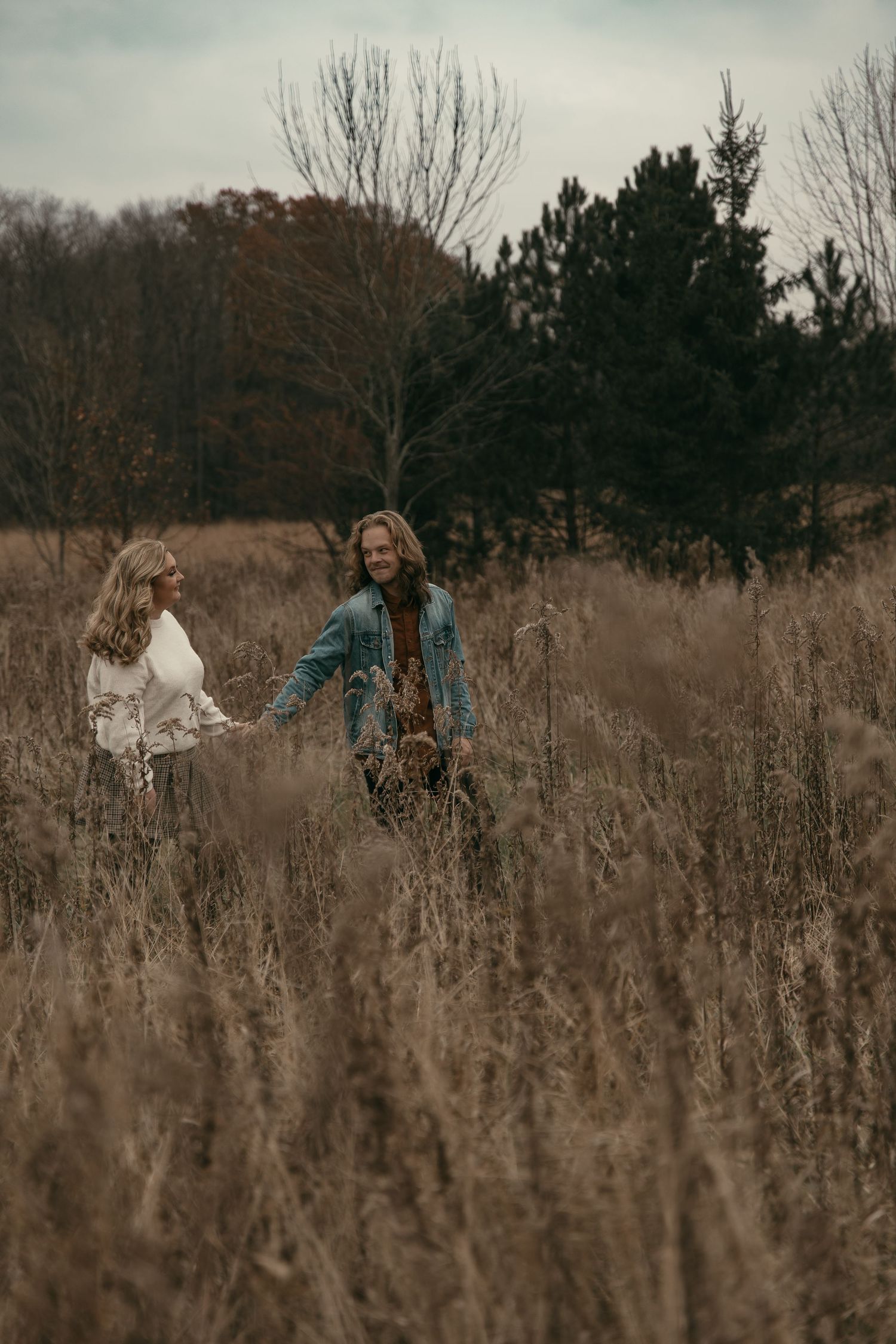 Dreamy couple walking in tall grass in Lake County Ohio by Gypsy Lens Photography. Moody, filmy, vintage, documentary wedding photography