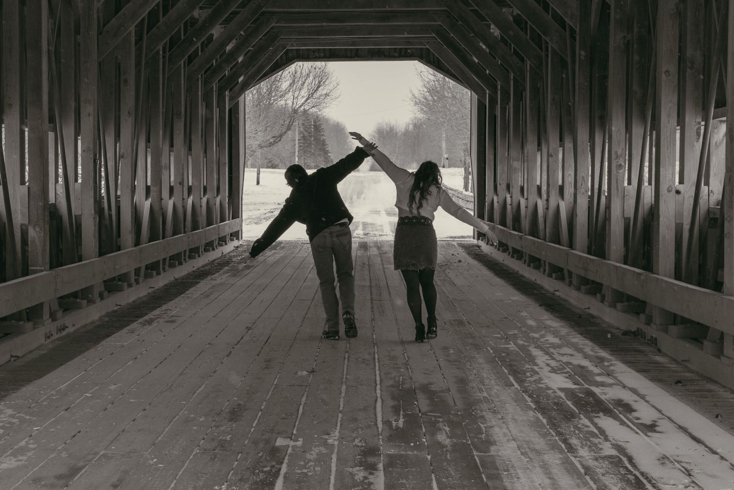Playful couple in covered bridge in Ashtabula Ohio by Gypsy Lens Photography. Moody, vintage, documentary wedding photography.