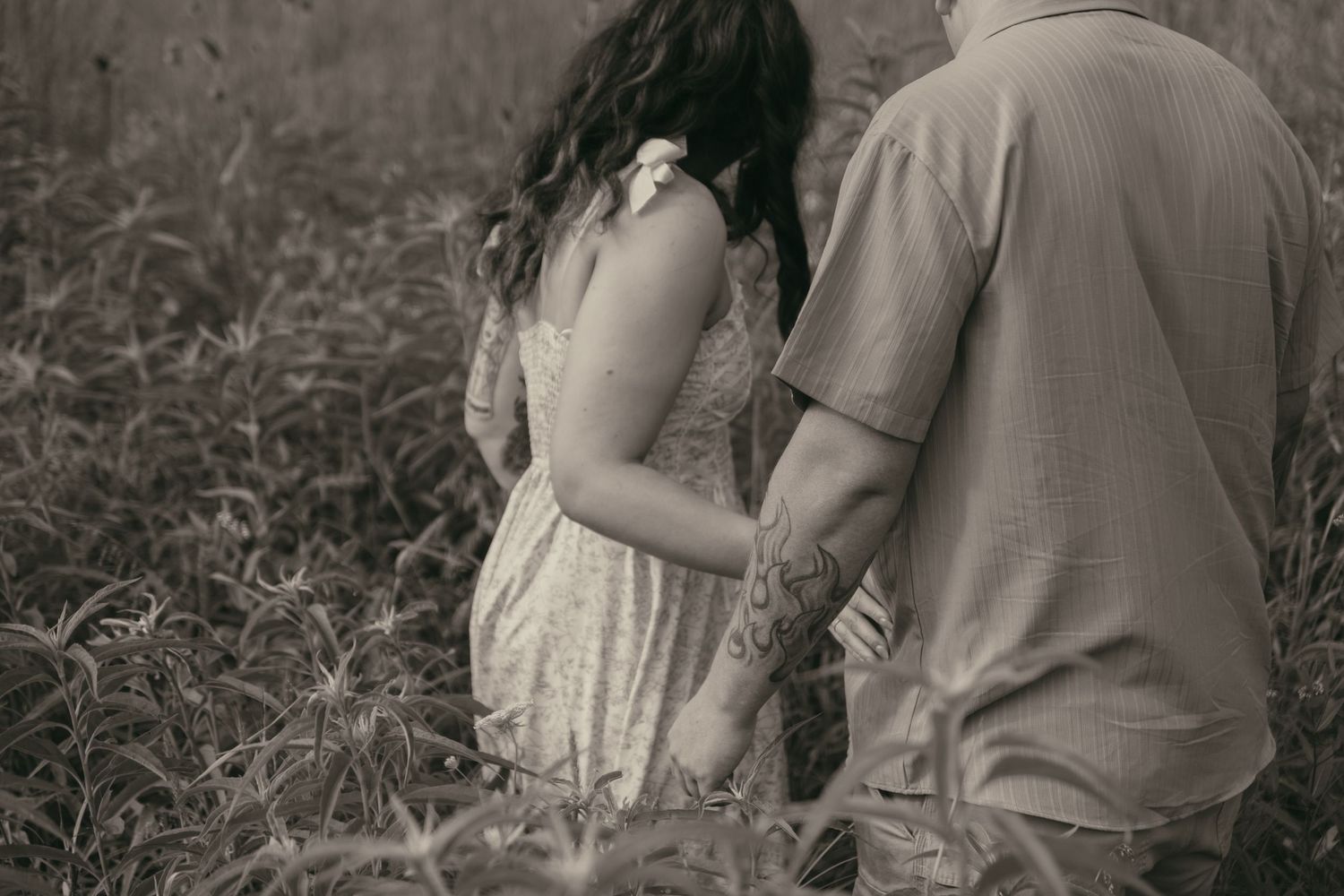 Engaged couple in a wildflower meadow in Lake County Ohio by Gypsy Lens Photography. Moody, filmy, vintage, documentary wedding photography