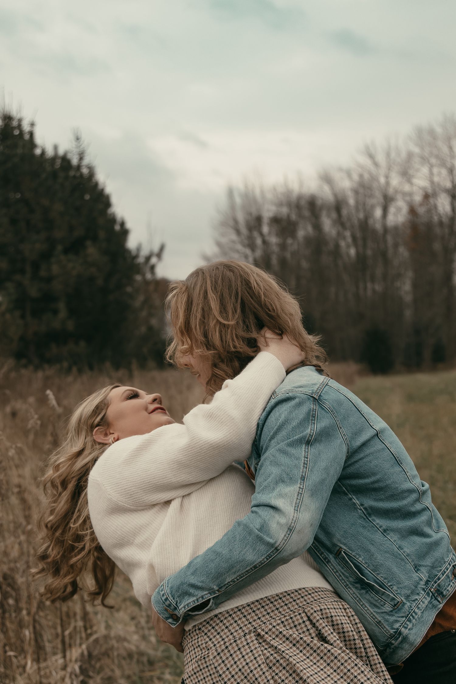 Engaged couple dance in tall grass in Lake County Ohio by Gypsy Lens Photography. Moody, filmy, vintage, documentary wedding photography