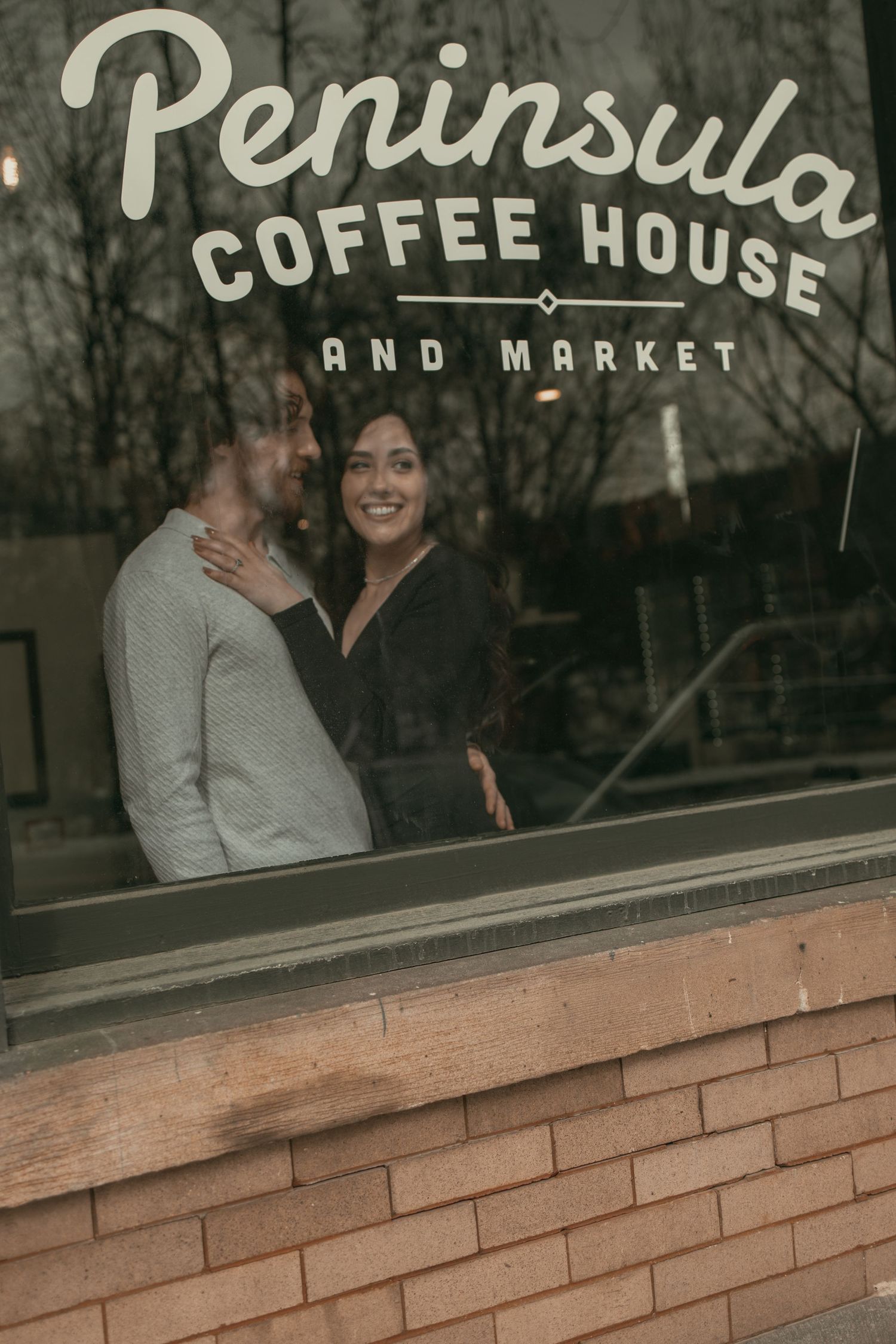 Cinematic window photo of engaged couple in Cleveland Ohio by Gypsy Lens Photography. Moody, vintage, documentary wedding photographer.