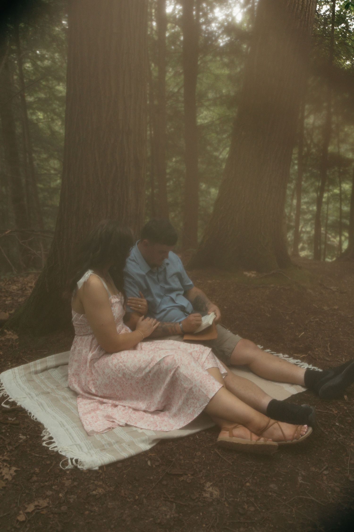 Engaged couple having picnic in woods in Lake County Ohio by Gypsy Lens Photography. Moody, filmy, vintage, documentary wedding photography