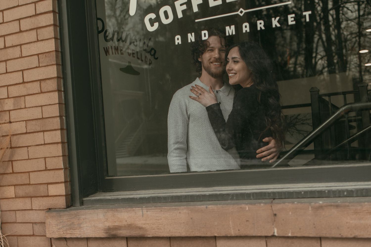 Cinematic window photo of engaged couple in Cleveland Ohio by Gypsy Lens Photography. Moody, vintage, documentary wedding photographer.