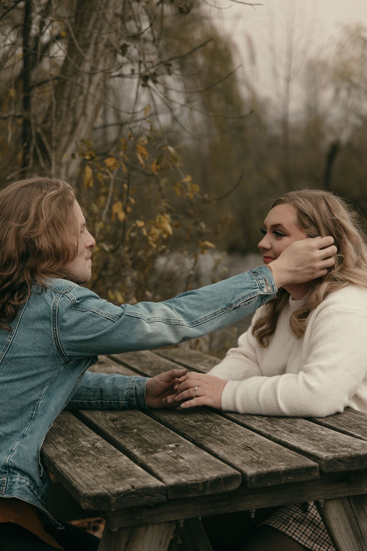 Engaged couple at picnic table in Lake County Ohio by Gypsy Lens Photography. Moody, filmy, vintage, documentary wedding photography
