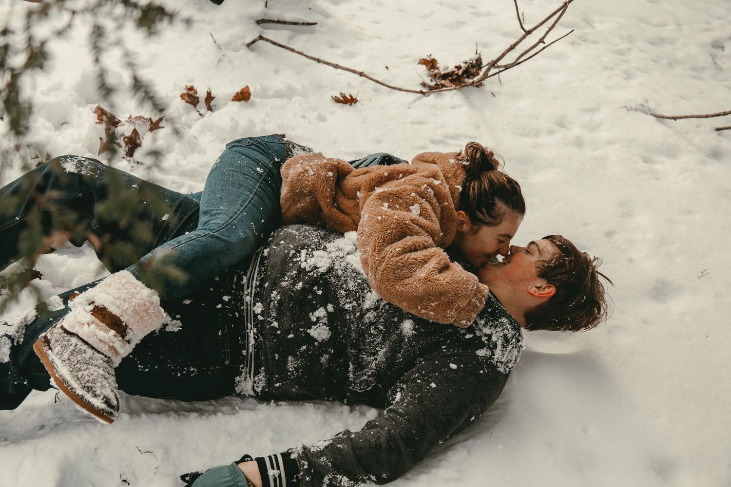 Engaged couple kissing in snow in Lake County Ohio by Gypsy Lens Photography. Moody, vintage, documentary wedding photographer.