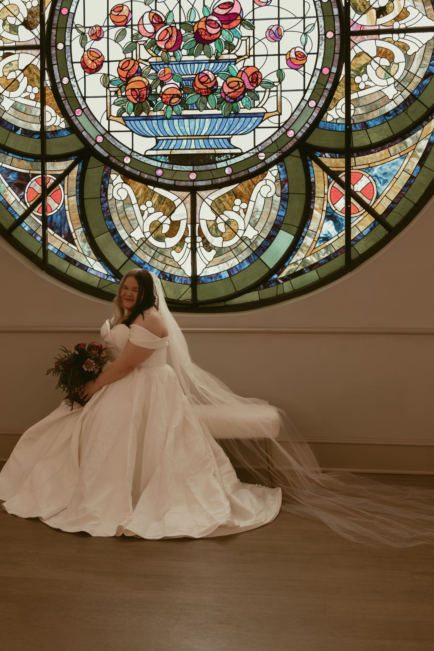 Bride sitting in front of stained glass in Cleveland Ohio by Gypsy Lens Photography. Moody, filmy, vintage, documentary wedding photography.